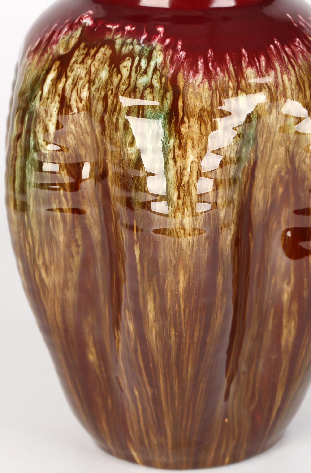 Un élégant vase attribué au mouvement esthétique Linthorpe, avec un corps pincé et émaillé en goutte d'eau, par Christopher Dresser (britannique, 1834-1904), datant d'environ 1885. Le vase en faïence rouge jeté à la main repose sur un pied étroit et
