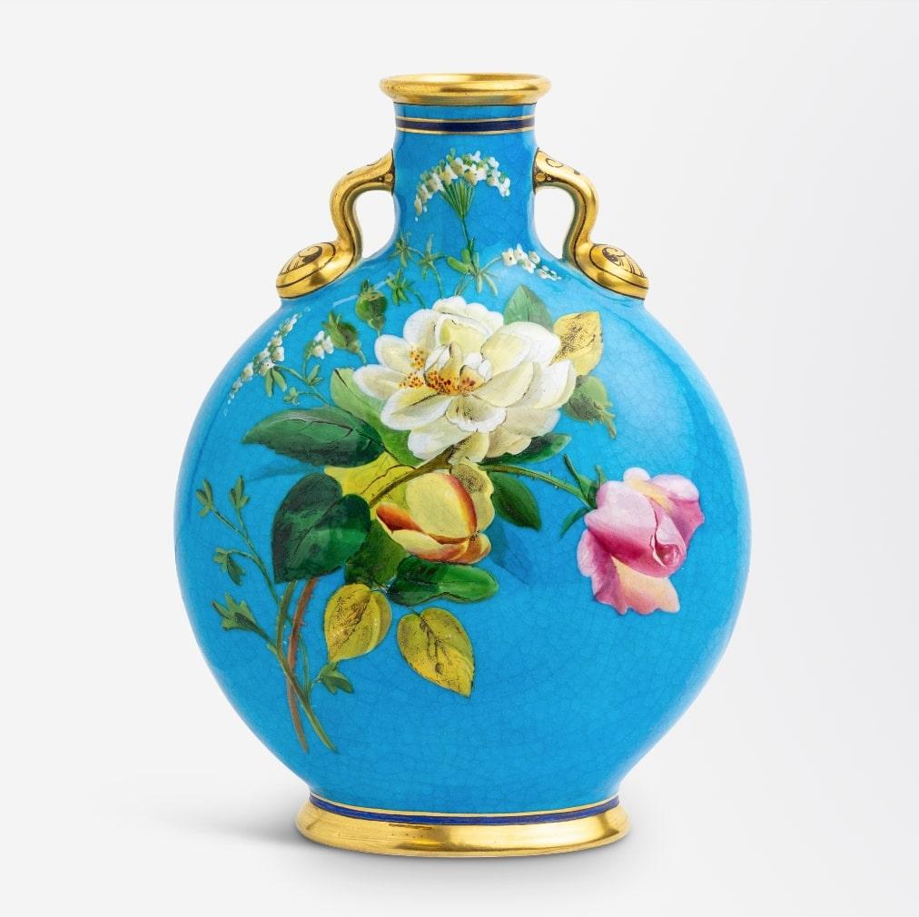Vase en forme de flacon de pèlerin à fond bleu, réalisé par le célèbre designer anglais Christopher Dresser pour Minton, vers les années 1870. Le motif de feuillage a probablement été peint à la main par William Mussill.

Dimensions : 20cm H x 15cm