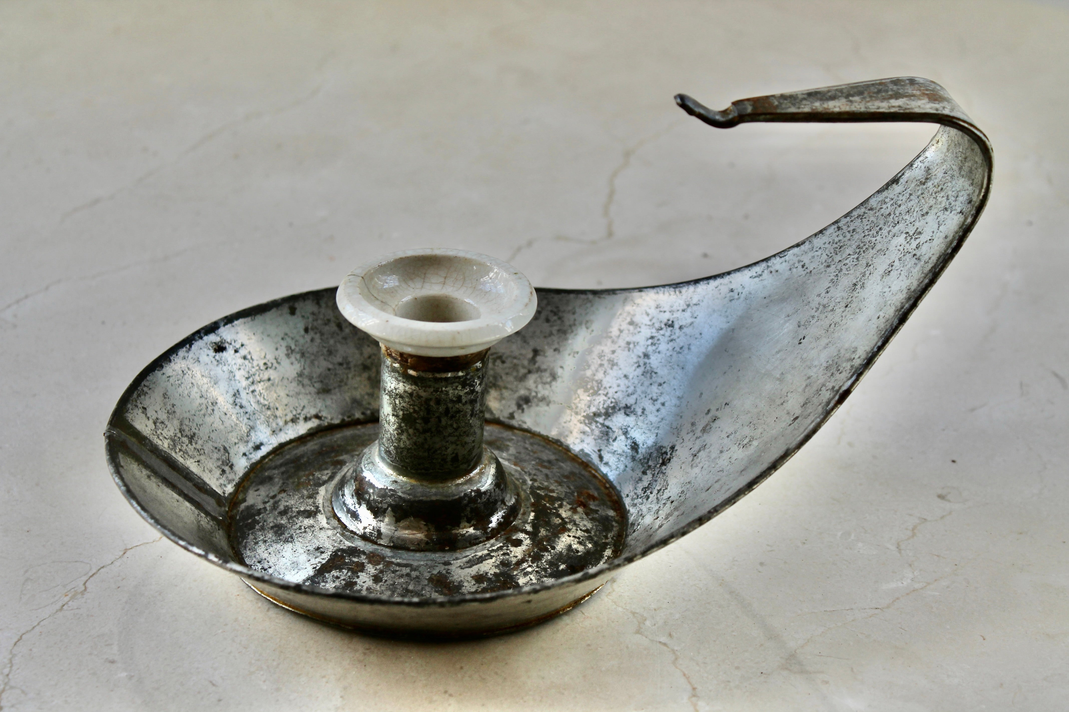A Christopher Dresser Aesthetic Movement candleholder, with a rare retaining of the original porcelain bobeche.  Signed with the Perry mark on the bottom. 