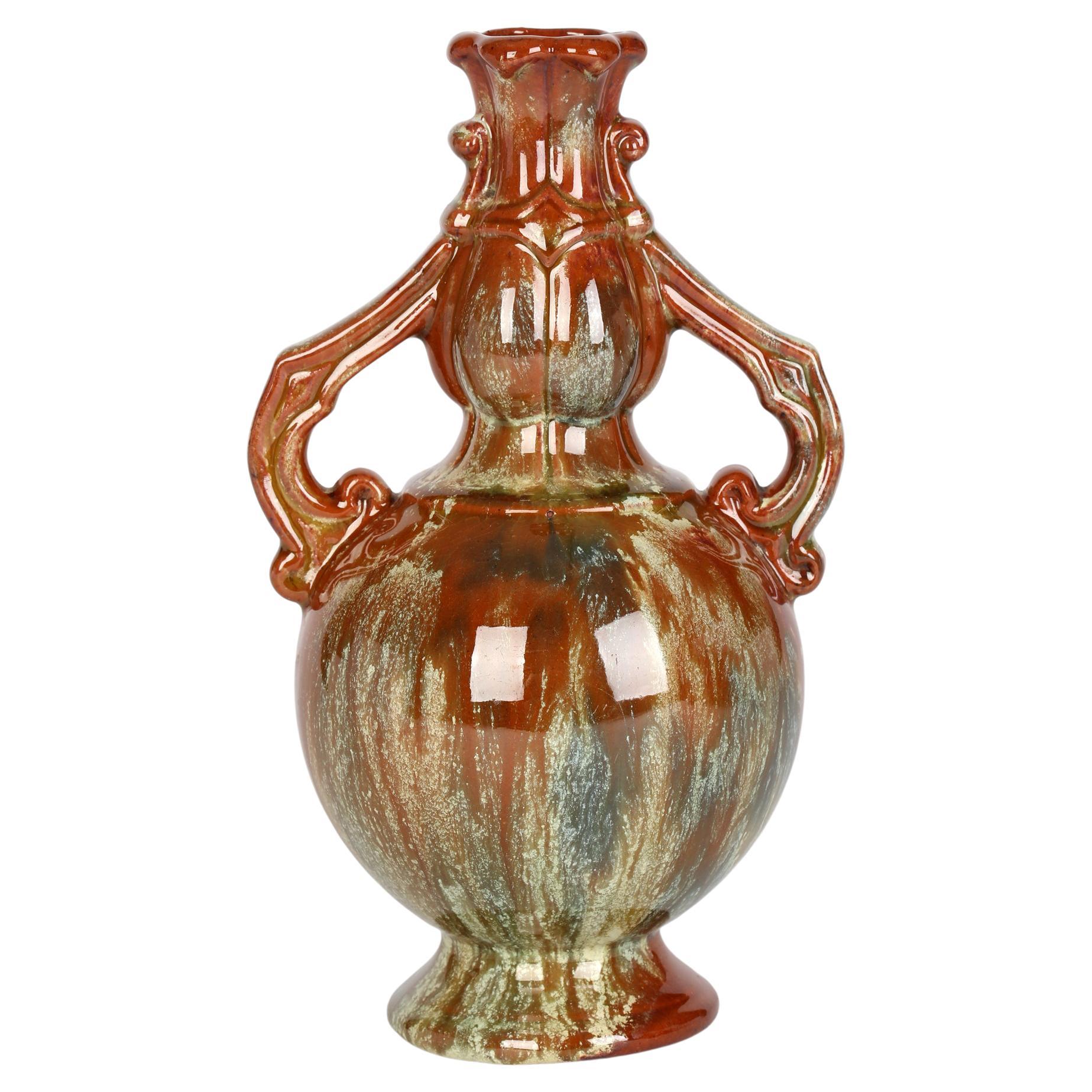 An unusual Aesthetic Movement flow glaze twin handled vase in the ‘Persian Taste’ by renowned British designer Christopher Dresser (British, 1834 – 1904) for Watcombe Torquay and dating from around 1885. The red earthenware vase is lightly potted