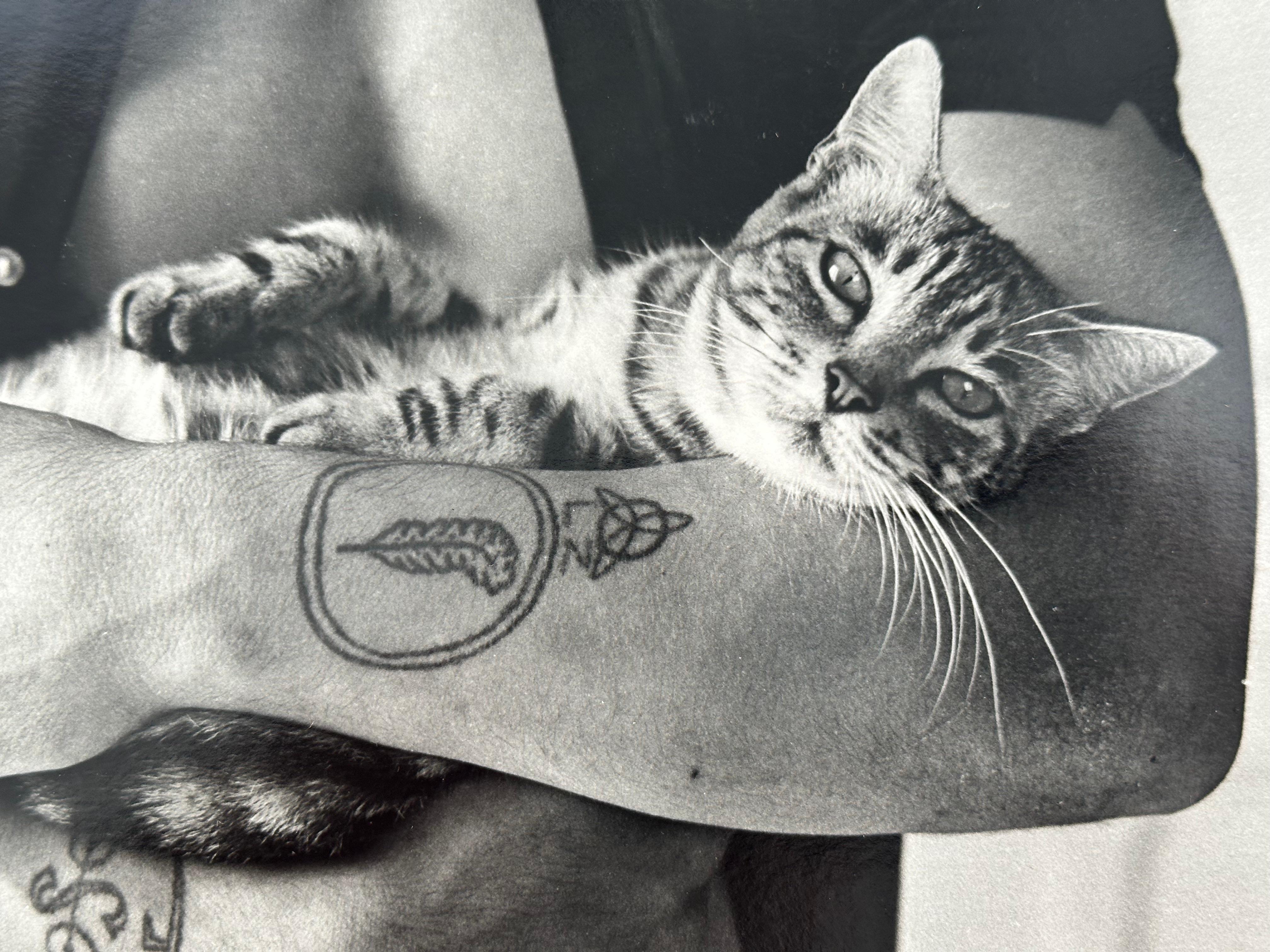 Christopher Makos, amerikanischer Fotograf, geb. 1948. Tätowierter Mann hält Katze, ca. 1970. Verso mit rotem Bleistift signiert.

Größe 8,25 x 10  Zoll. Ungerahmt und unmontiert.

Dieses Beispiel war ein Pressefoto, das an die Büros des After Dark