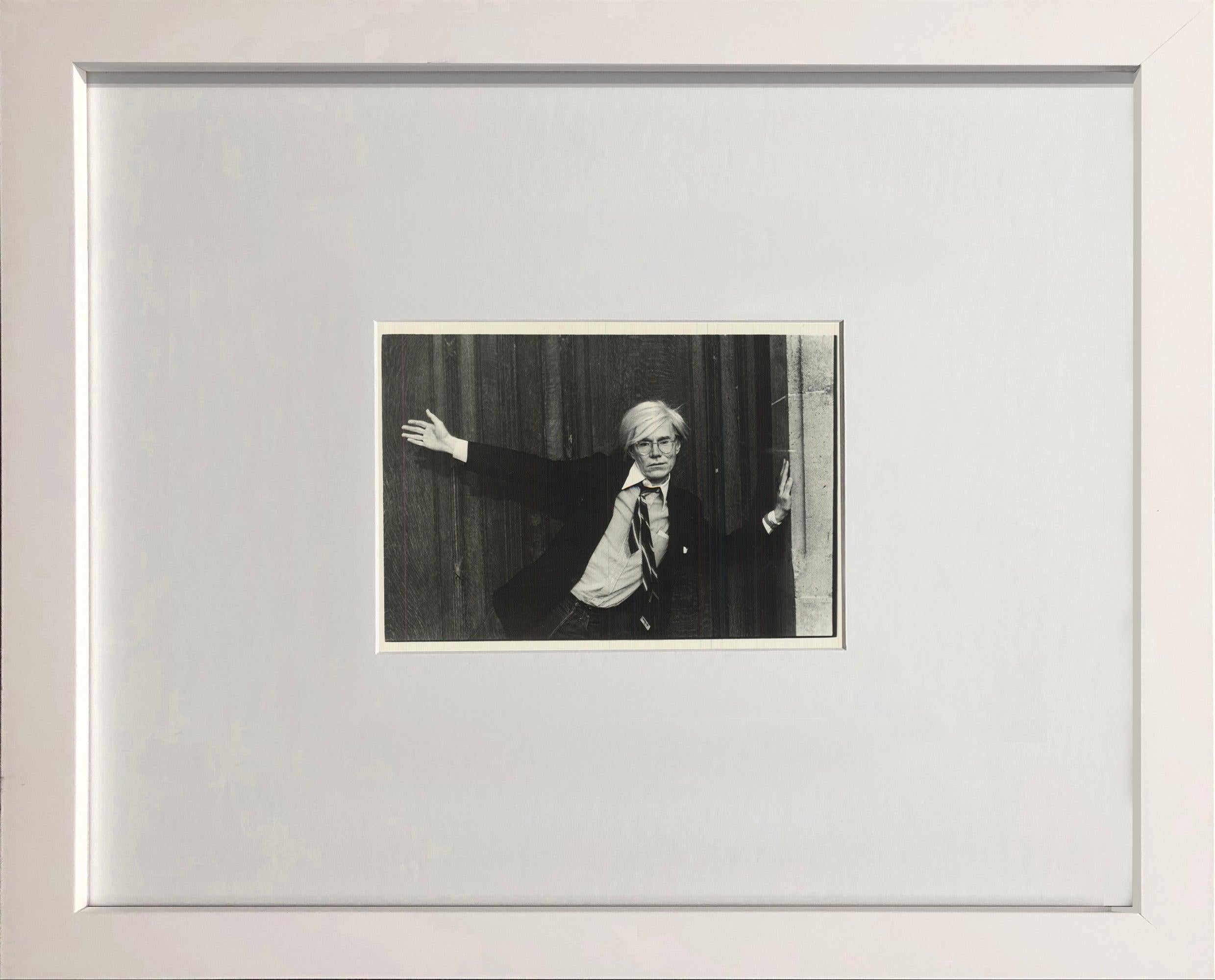 This vintage postcard features a photographic portrait of Andy Warhol by Christopher Makos, one of the artist's closest collaborators and most important photographers. The image captures Warhol in a candid yet theatrical pose, reflecting the