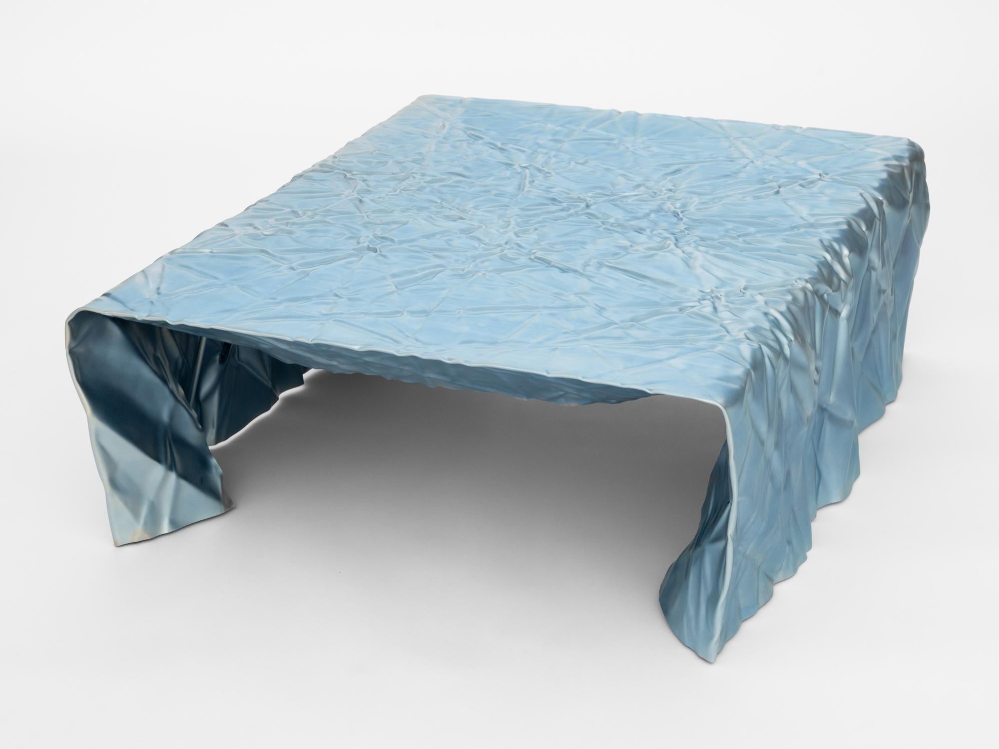 Table basse en acier froissé du designer Christopher Prinz, basé à Omaha, qui obtient cette texture inhabituelle en froissant à plusieurs reprises une fine feuille d'acier, ce qui donne une forme solide, rigide et unique. Les pieds de nivellement