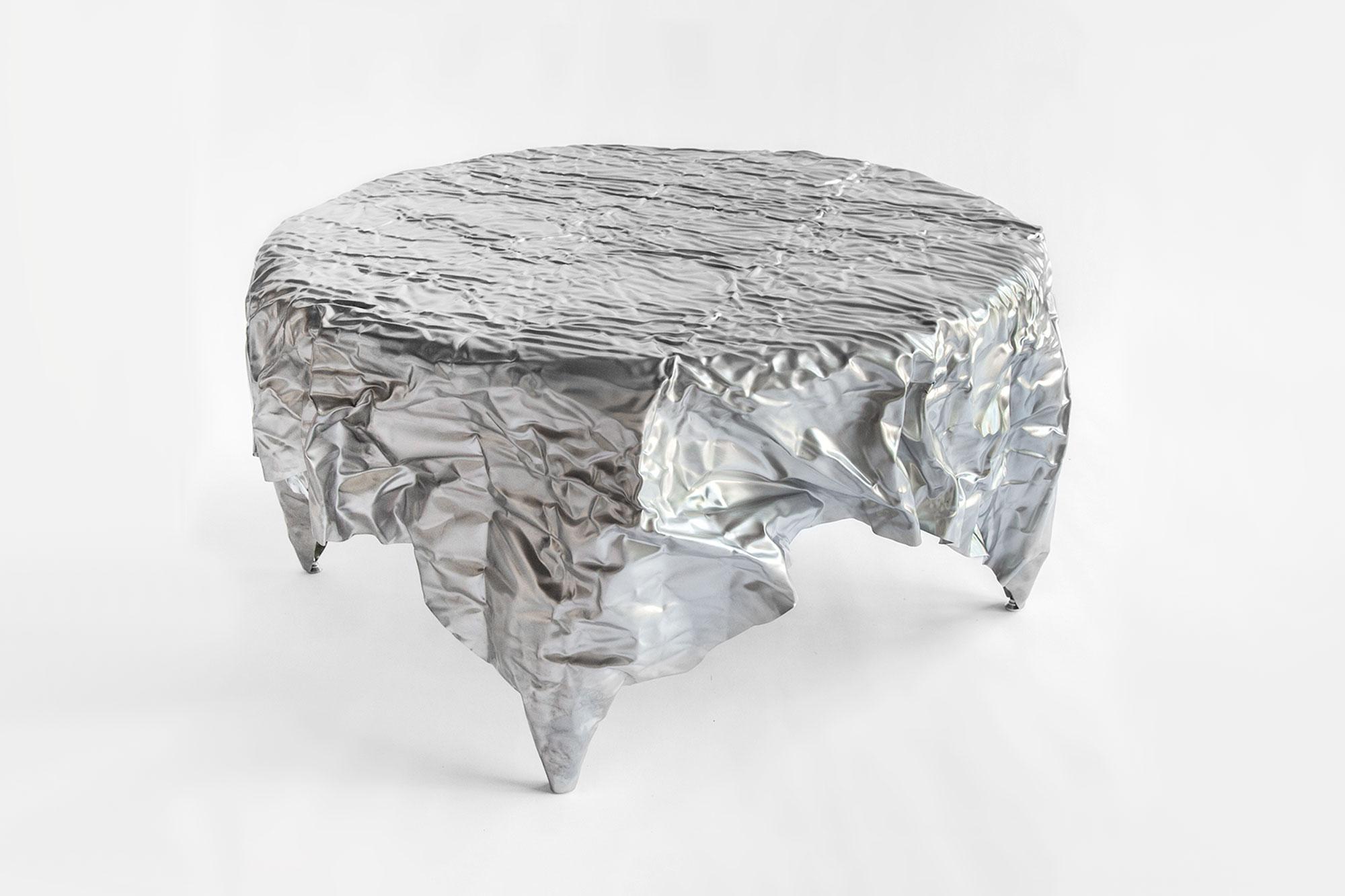 Table basse en acier froissé du designer Christopher Prinz, basé à Omaha, qui obtient cette texture inhabituelle en froissant à plusieurs reprises une fine feuille d'acier, ce qui donne une forme solide, rigide et unique. Les pieds de nivellement