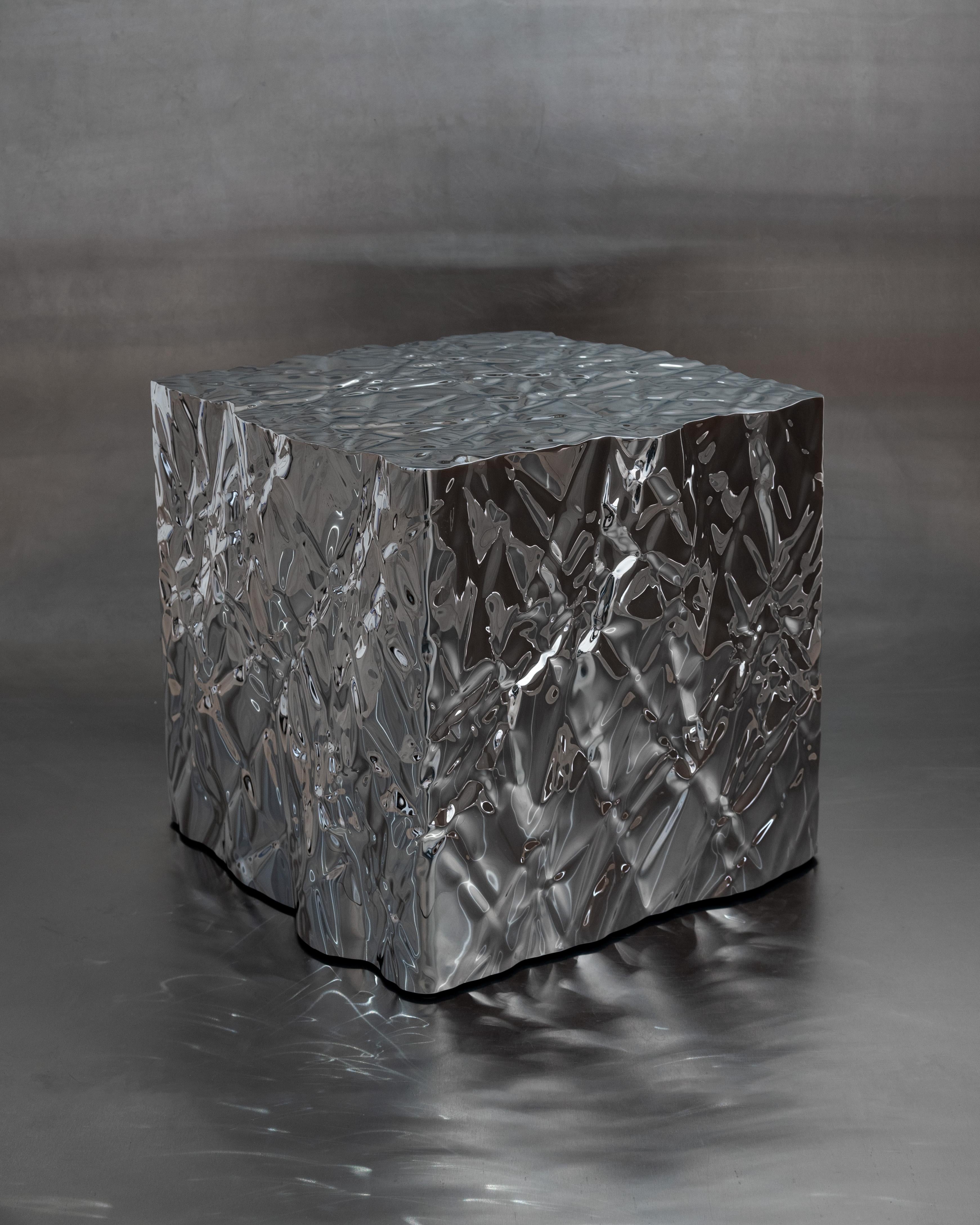 Wrinkled steel cube side table by Omaha-based designer Christopher Prinz, who achieves this unusual texture by repeatedly creasing a thin sheet of steel, resulting in a strong, rigid, and unique form. Hidden leveling feet protect surfaces and ensure