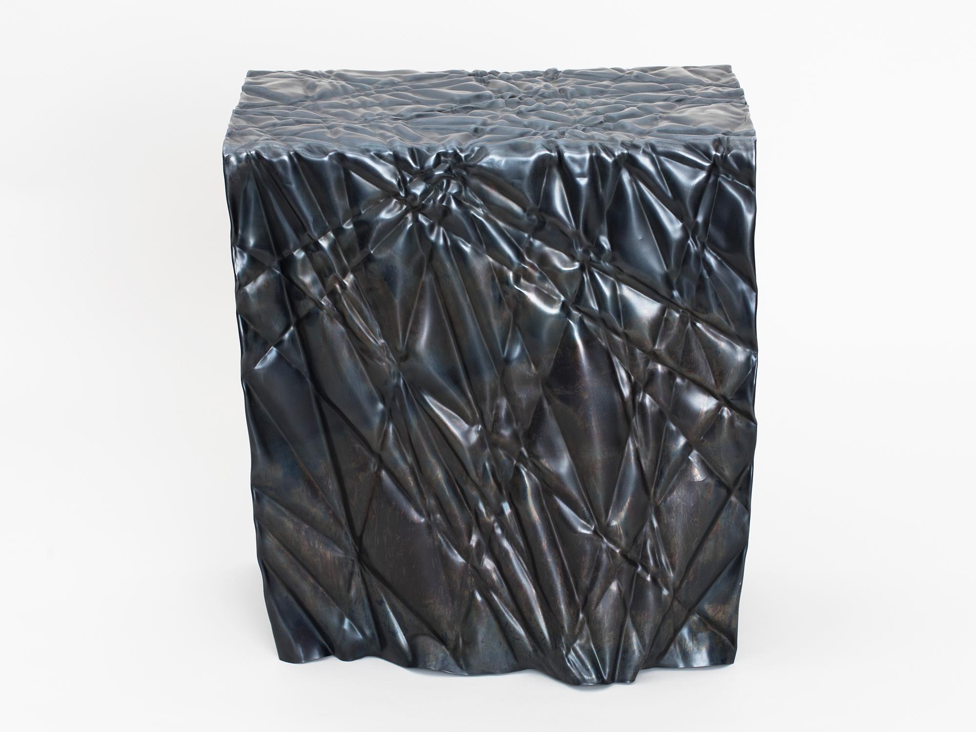 Wrinkled stool or side table by Omaha-based designer Christopher Prinz, who achieves this unusual texture by repeatedly creasing a thin sheet of steel, resulting in a strong, rigid, and unique form. Hidden leveling feet protect surfaces and ensure