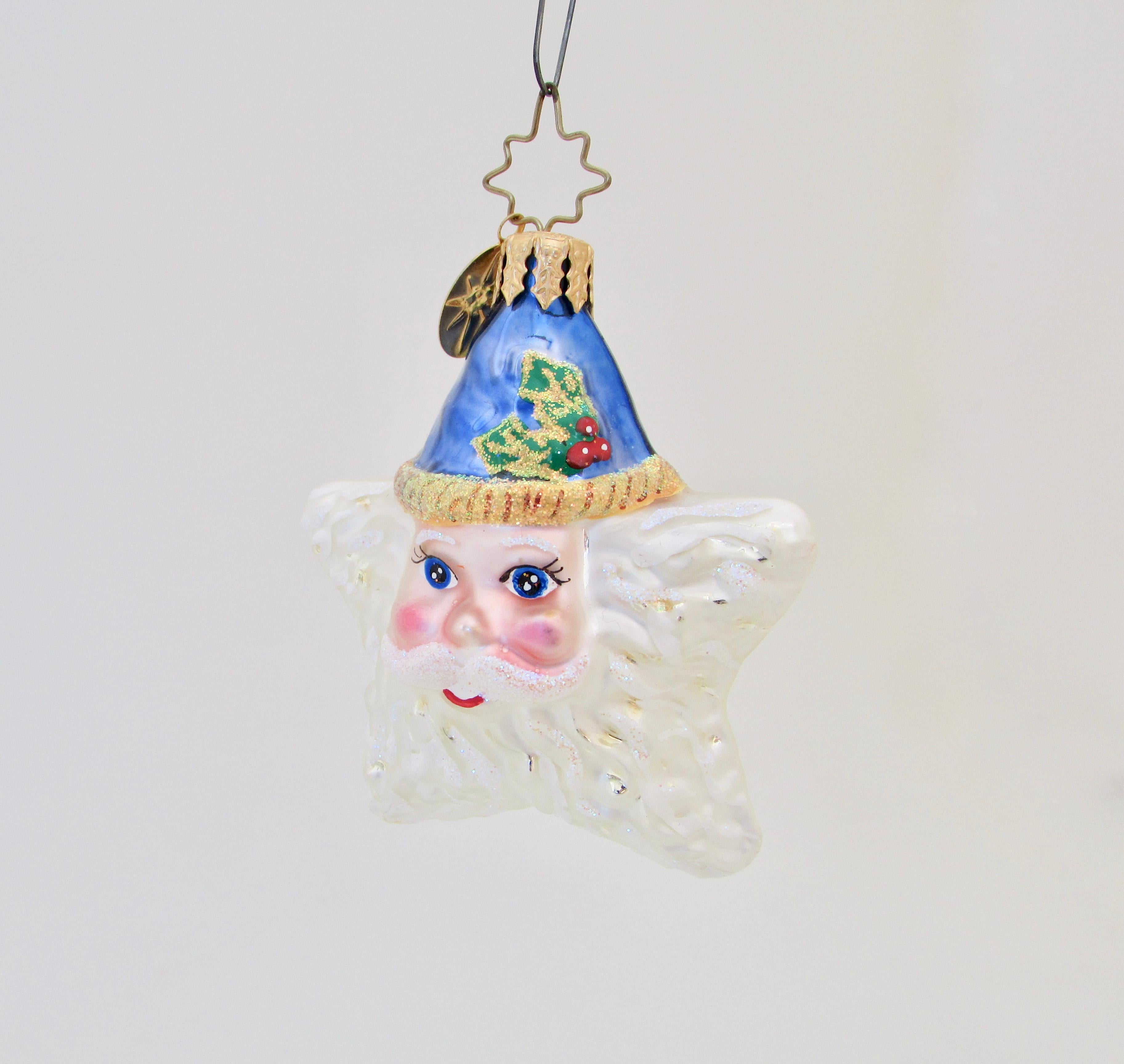 Vintage Christopher Radko double-sided Christmas ornament Shine On Santa shaped as a star with full white beard and holly adorned blue hat. Flocked throughout.   

Family-owned European factories use centuries-old techniques to blow, silver,