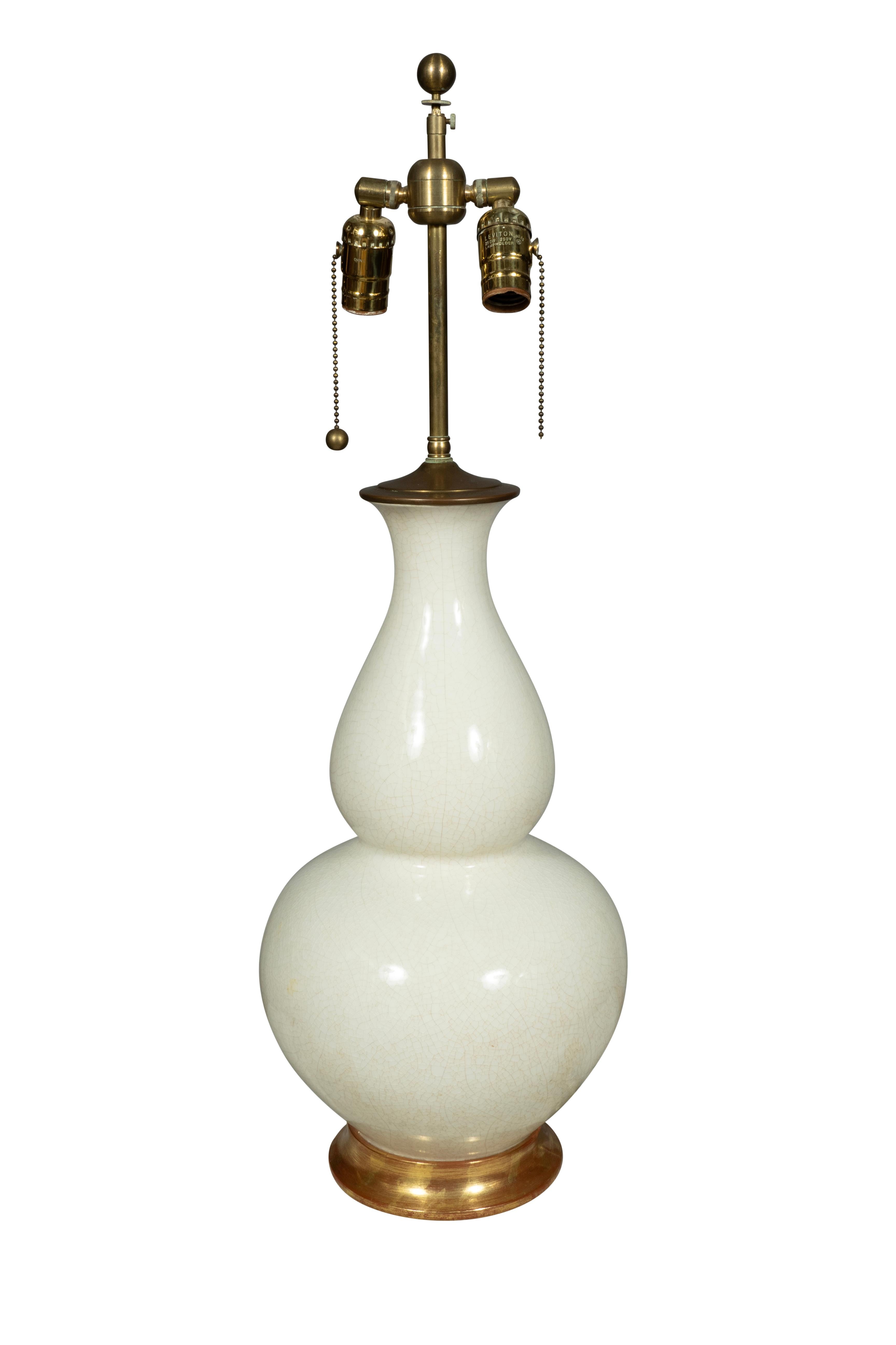 Blanc de Chine forme de double gourde avec deux luminaires. Base dorée à l'eau. Signé sous la base.