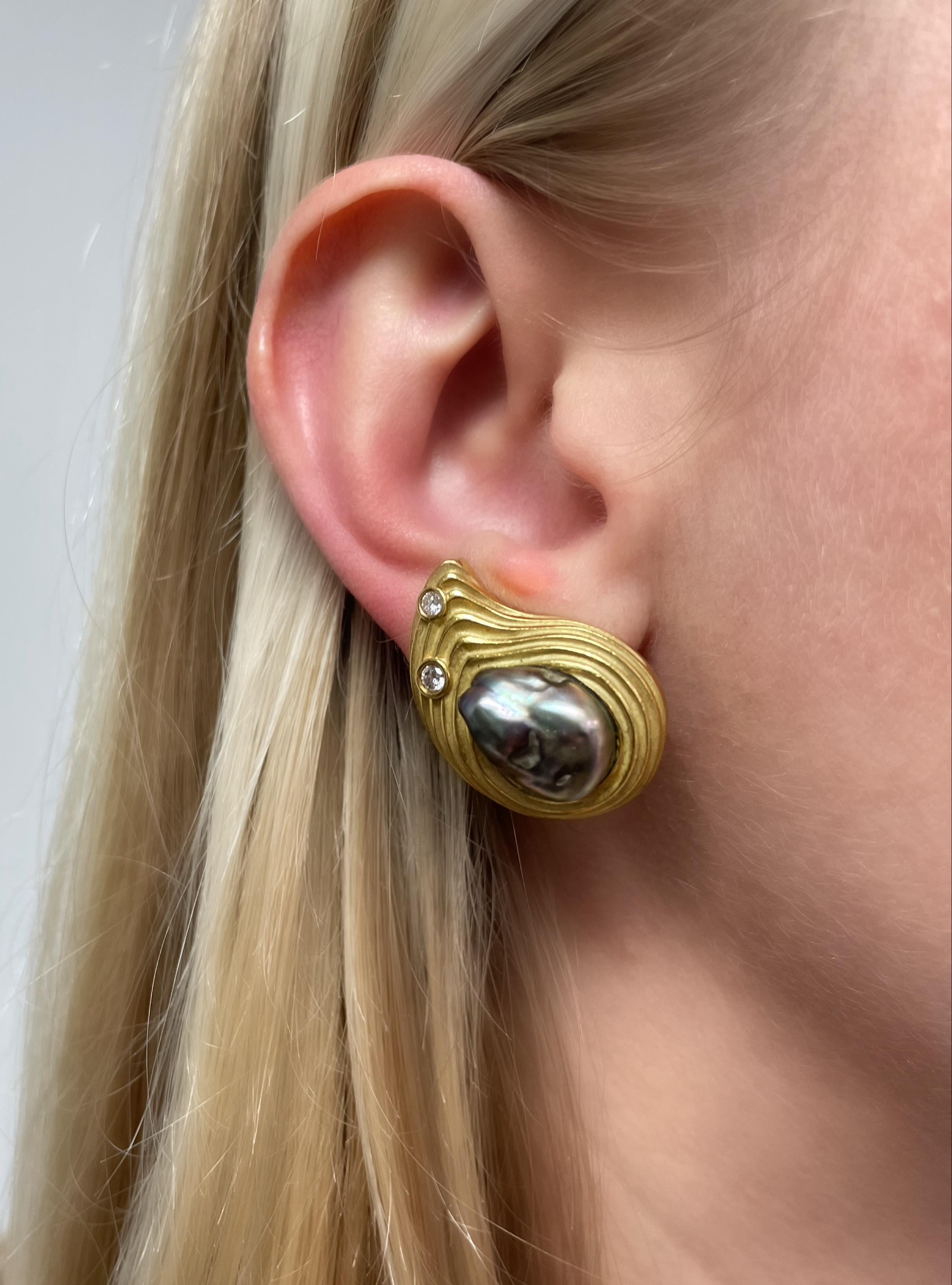 These classic Christopher Walling earrings are designed in a paisley shape with cultured grey Baroque pearl centers, four round brilliant cut diamond accents and a matte finish ridged surround.

Stamp: C. WALLING
Earclip stamp: 14K
Measurement: 1