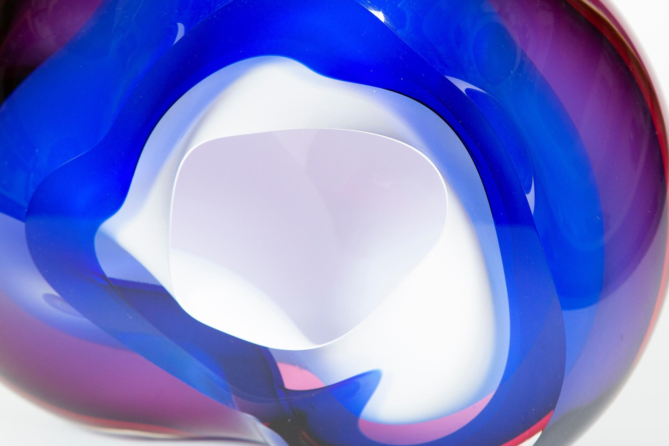Chromatic Vug in Blue and Fuchsia is a unique handblown sculpture by the British artist Samantha Donaldson. Created by layers of coloured glass in blue and fuschia, surrounding an inner layer of opaque white, the outer transparent colours merge and