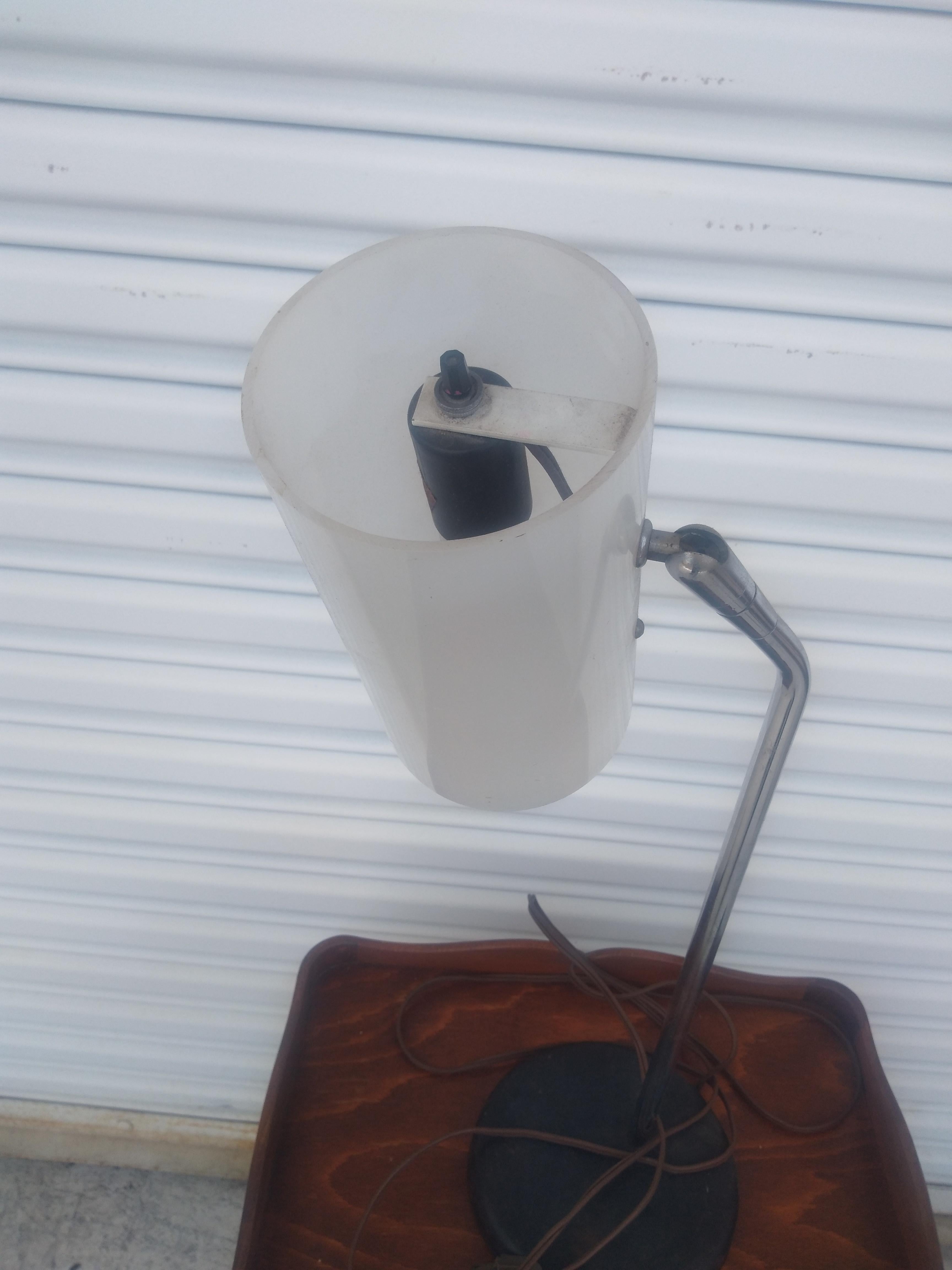 This is a 1970's Chrome Adjustable Table Lamp. It comes with the cylindrical lucite shade. The base is black weighted steel to give this lamp stability.