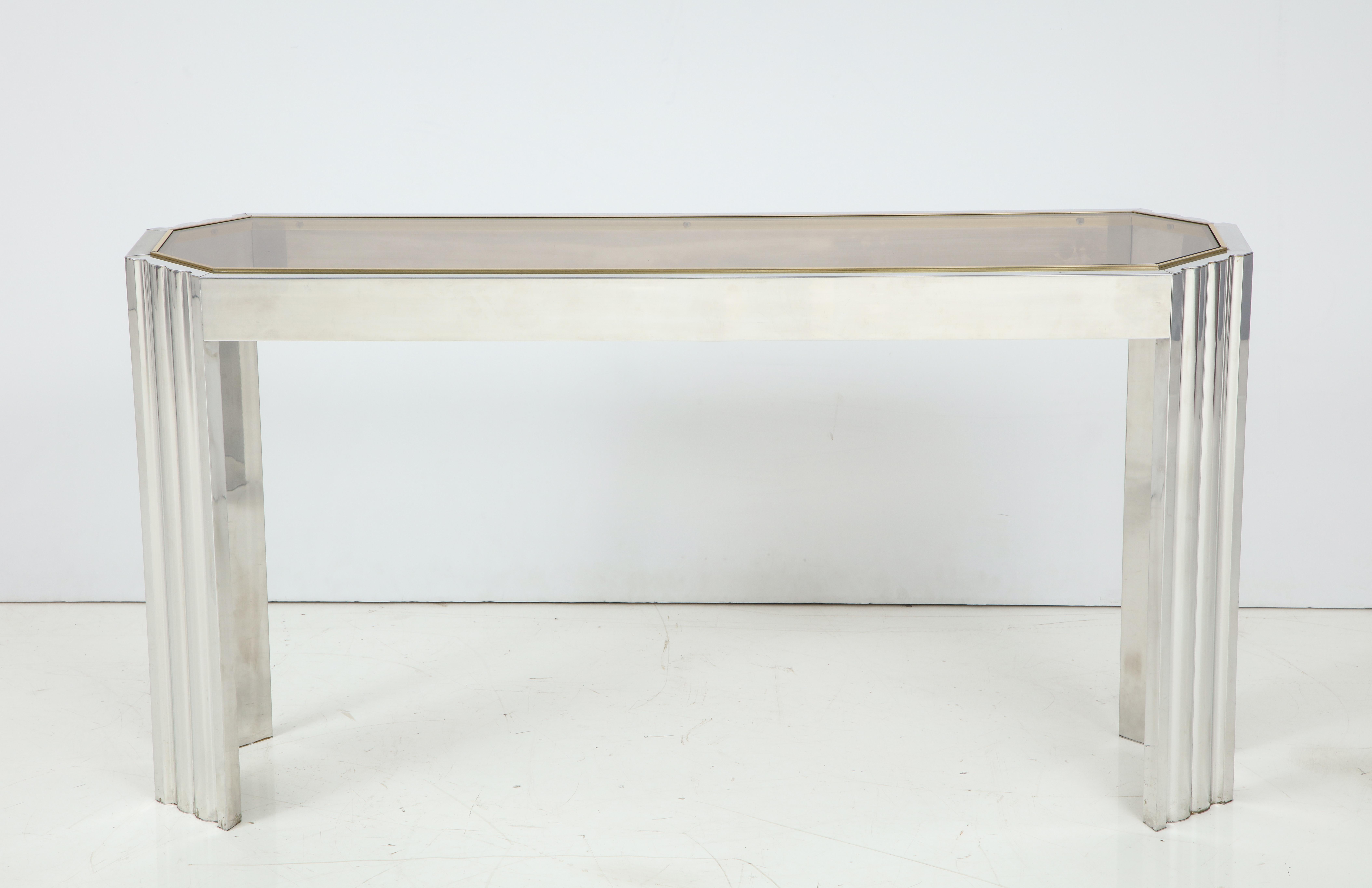 A 1970s chrome console table with octagonal shaped inset smoked glass top surrounded by brass trim.