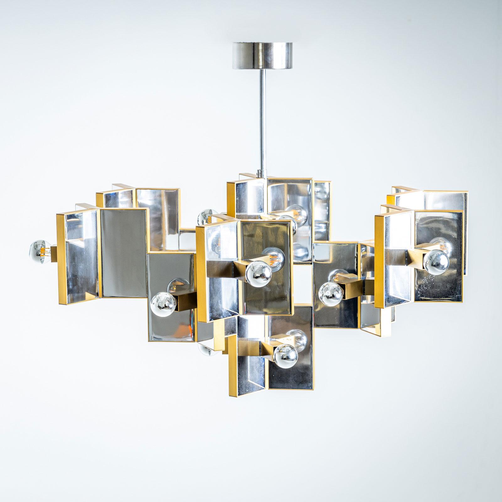 

Un grande lampadario del famoso designer Gaetano Sciolari, realizzato in Italia negli anni Settanta. Questo grande lampadario presenta una combinazione di cromo lucido e ottone, creando un'estetica lussuosa e senza tempo.

Il design presenta una