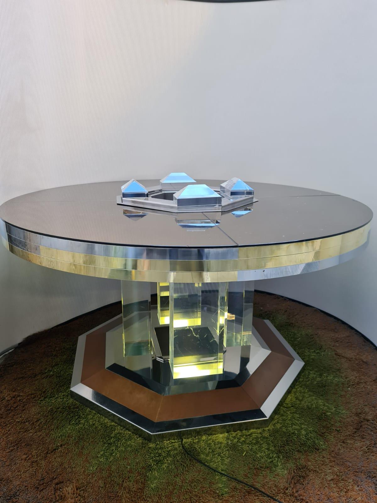 Exclusive chic round dining table by Sandro Petti for Maison Jansen,France, 1970s. High-end piece that fits well in a Hollywood regency decor. From a brass and chrome octagonal base, four huge Lucite column rise to hold the impressive round top,
