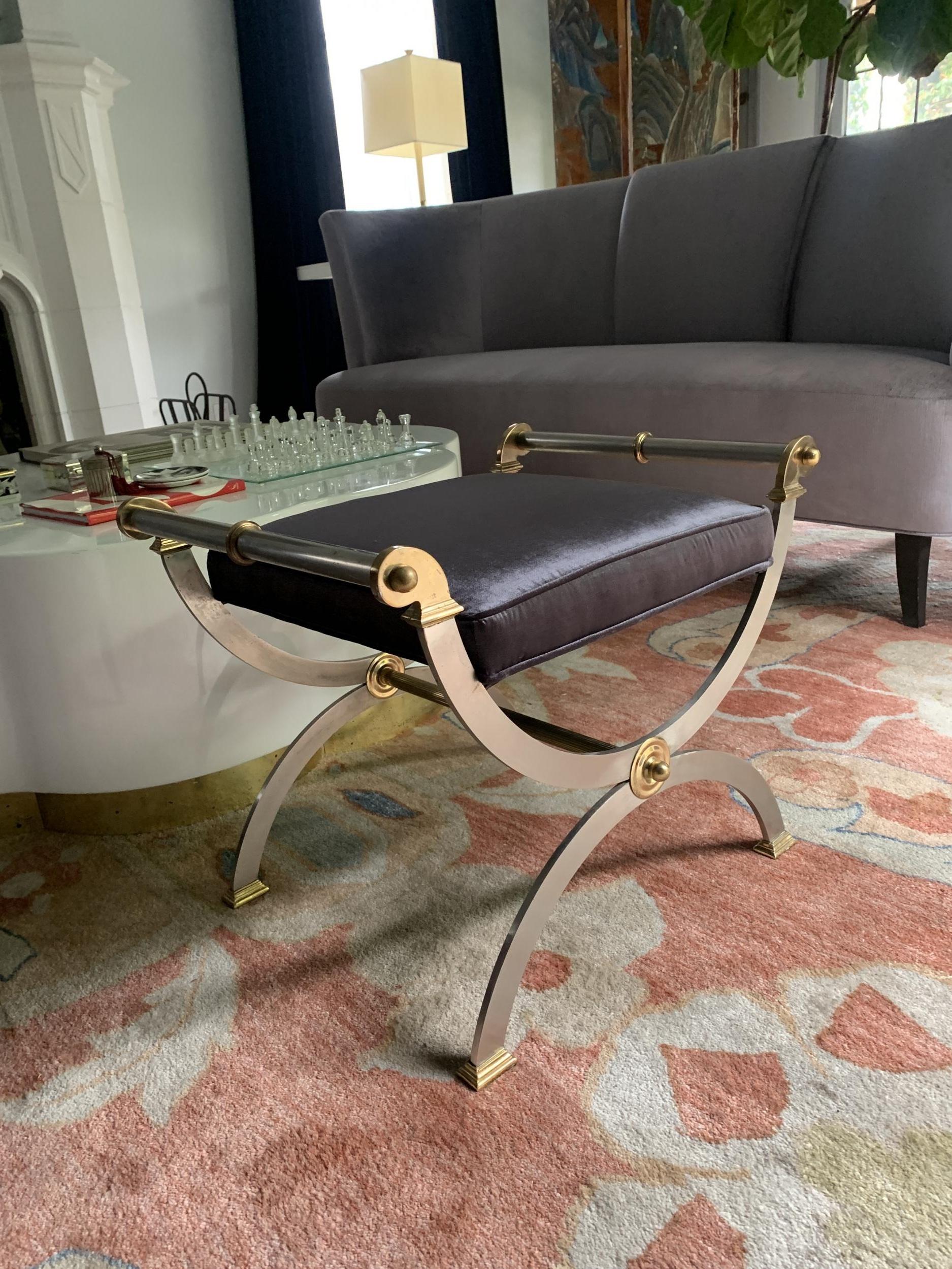 Brushed chrome midcentury bench inspired shape of a Savonarola - the rounded legs are met with brass handles, brass feet and joined by brass medallions. An architecturally sexy design likely to be from the 1970s-1980s. 

Perfectly suited for the