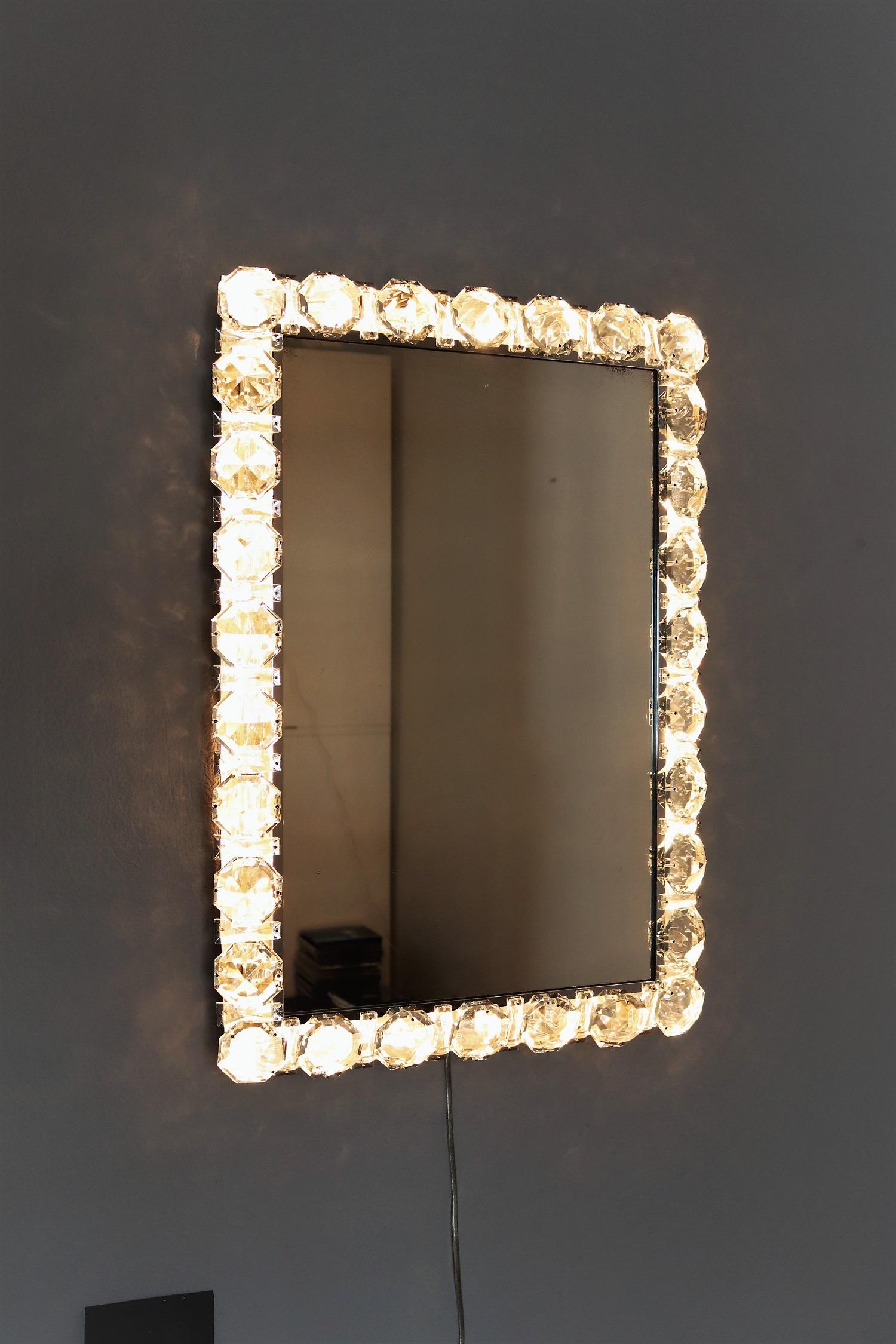 A real luxury wall mirror with many big size (2,4in or 6 cm) shiny crystals around the chrome-plated rounded mirror frame with inbetween smaller square crystals.
The mirror can be illuminated from inside and creates a gorgeous brilliant light. Much