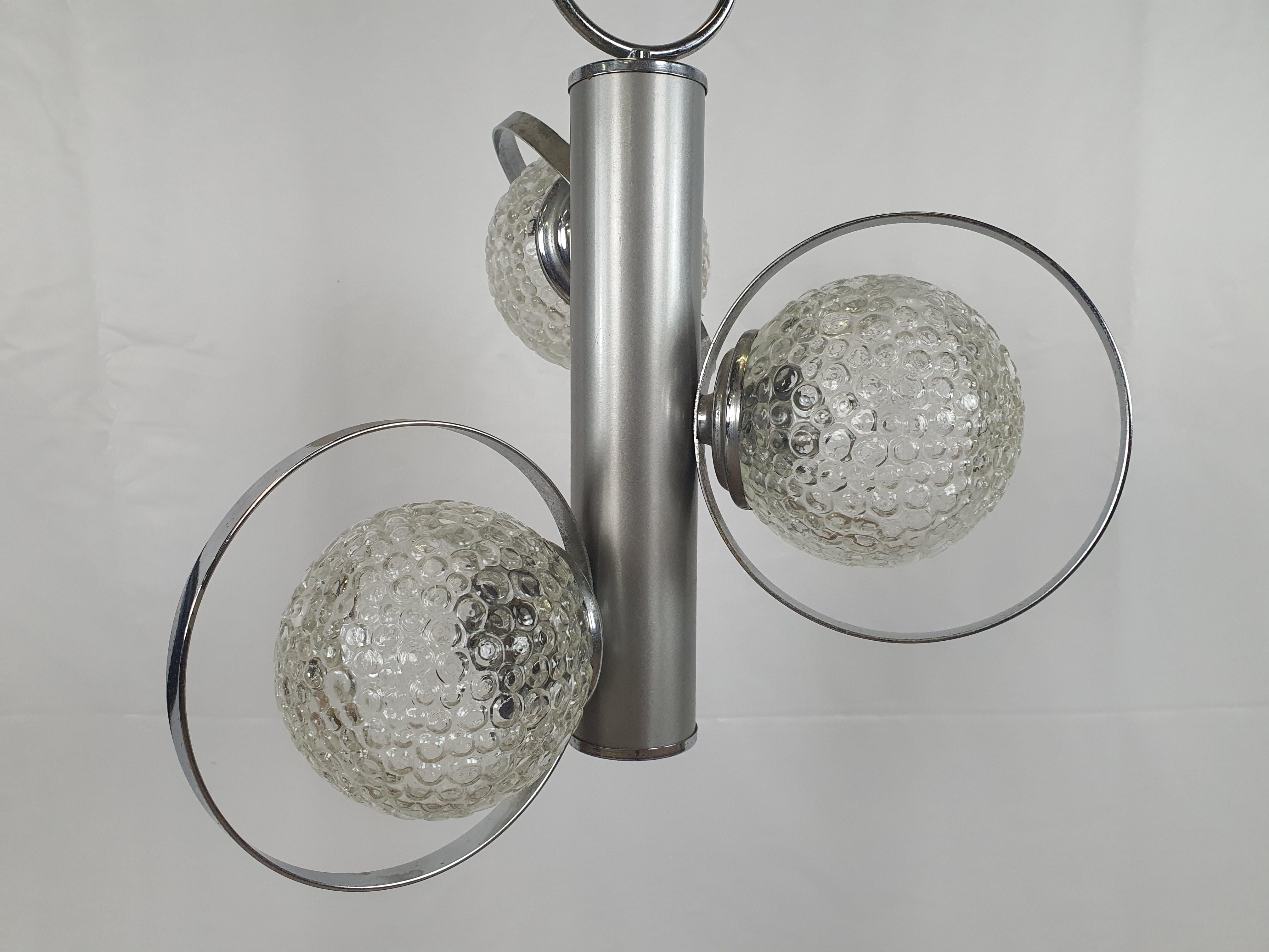 Italienischer Metallkronleuchter aus den 1970er Jahren mit 3 Lichtpunkten in gearbeiteten Glaskugeln.

Hat normale alters- und gebrauchsbedingte Gebrauchsspuren.
Wir empfehlen, die elektrischen Teile und/oder die elektrische Anlage zu ersetzen,