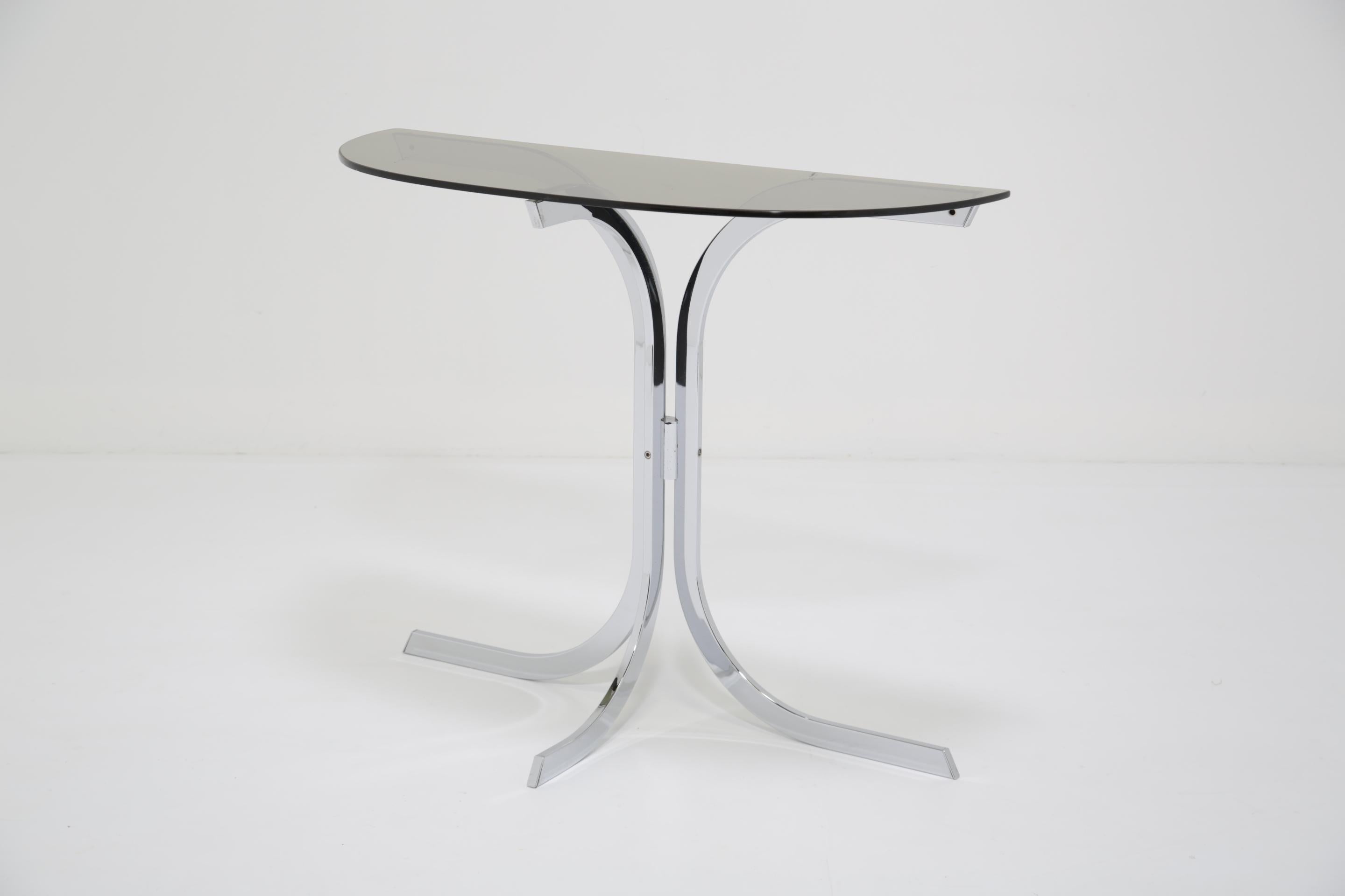 Jetez un coup d'œil à cette nouvelle arrivée ici à The Vintage Hub, une table console minimaliste à trois pieds dotée d'une élégante structure incurvée en chrome poli et associée à son plateau en verre fumé d'origine. Un design simple mais beau,