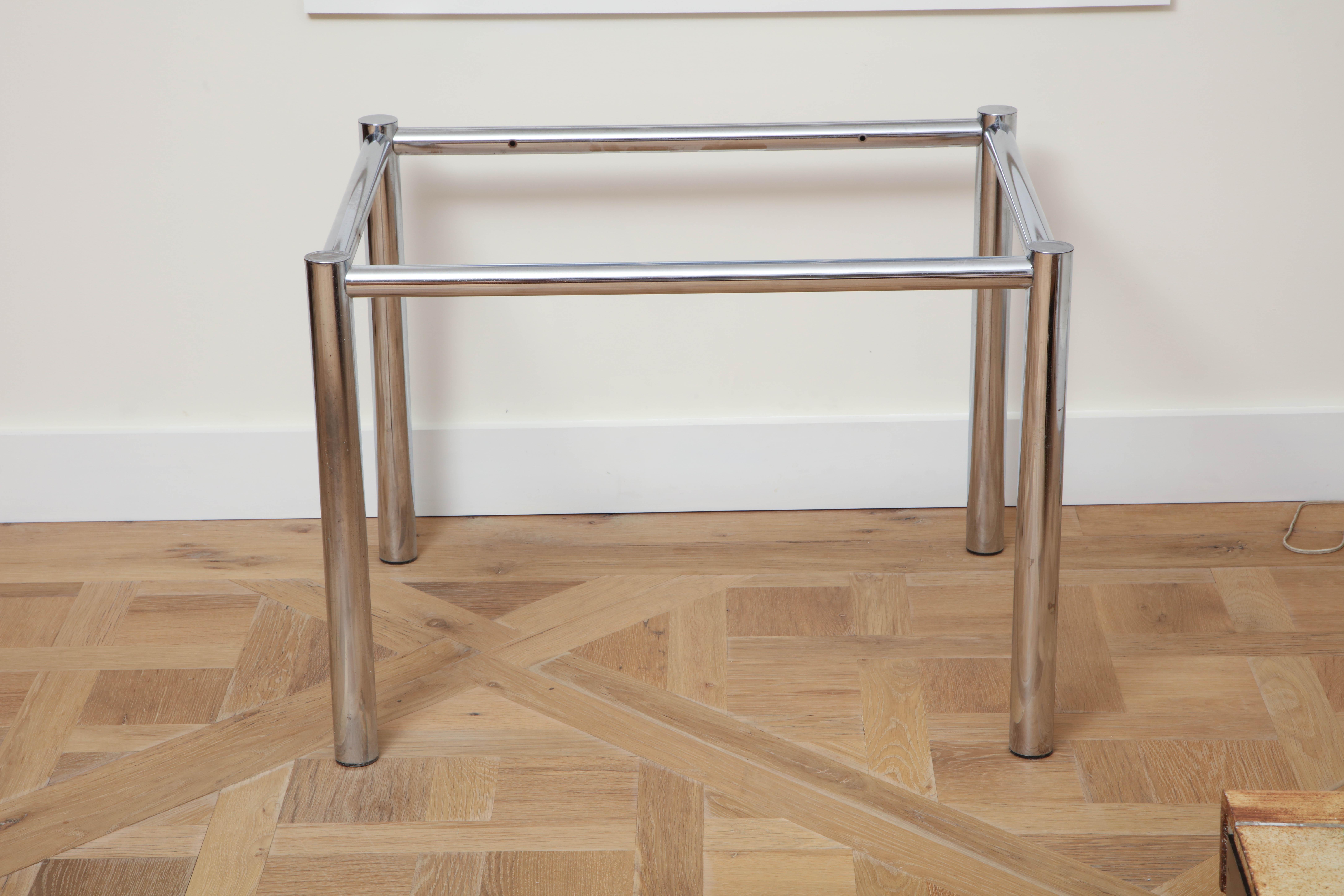 The rectangular (but nearly square) glass top inset into the chrome table frame; raised on round straight legs.