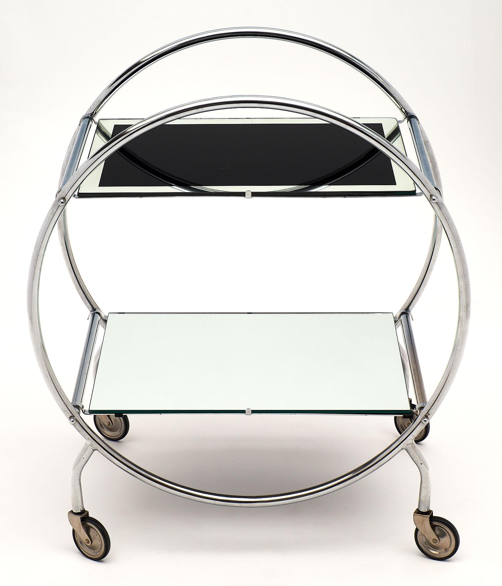 French vintage iconic bar cart of circular form, the original Mid-Century Modern structure supports original black glass shelf with a mirrored edge on the top and a mirrored shelf below.
