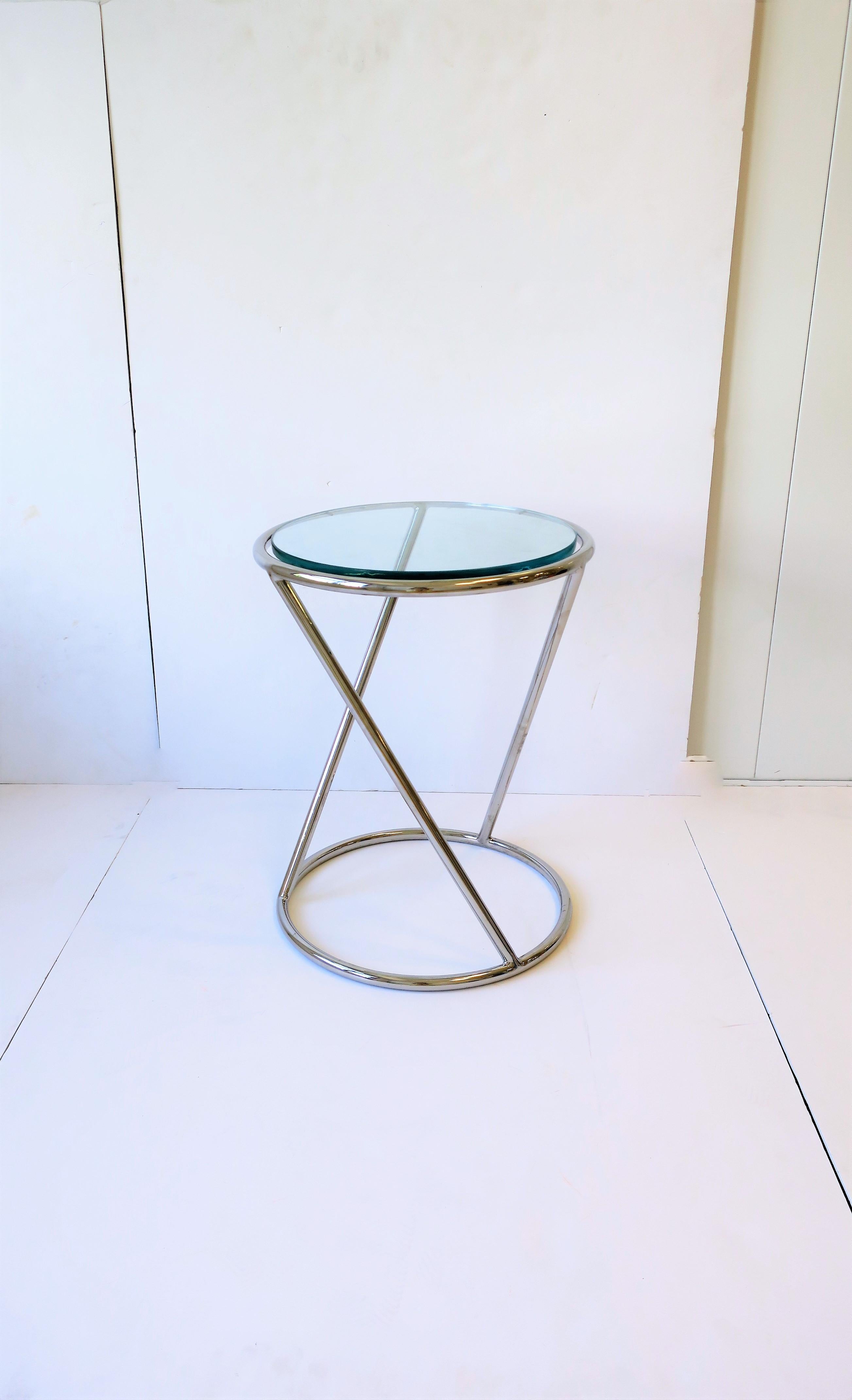 A chrome round side or drinks table with substantial glass top in the style of Modern, circa late-20th century. Dimensions: 14.25
