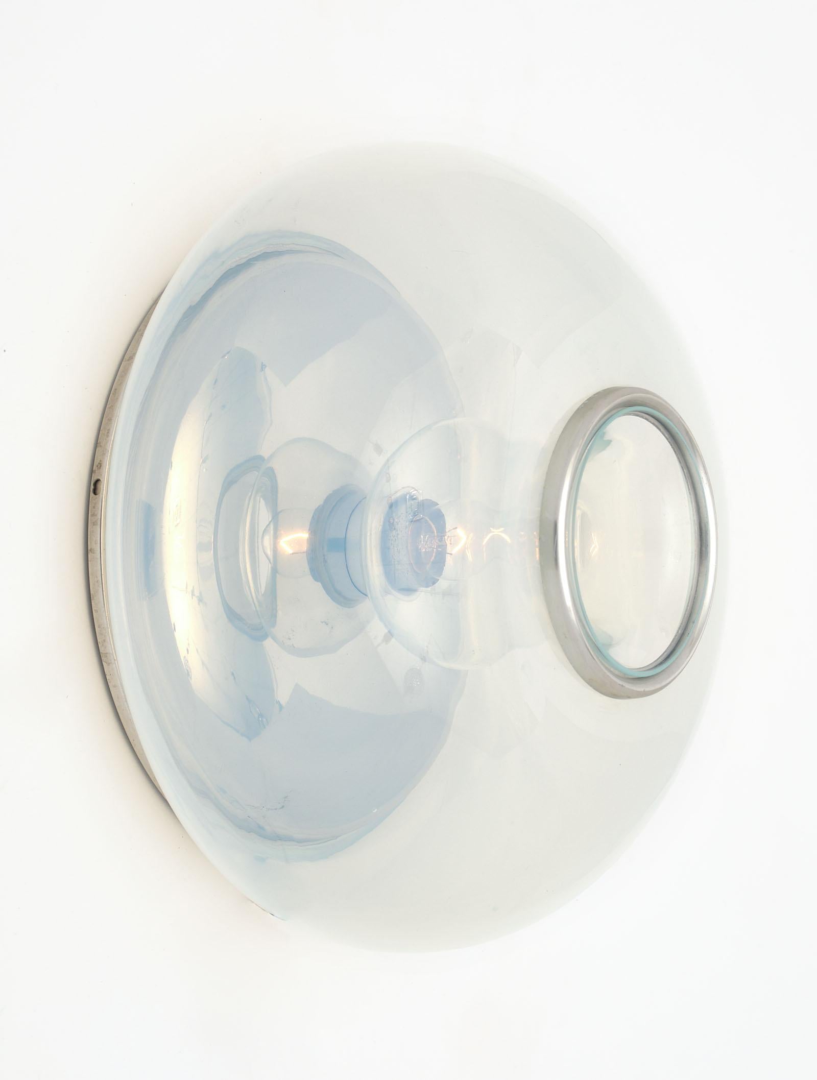 Chrome and glass sconces by Giuliana Gramigna in a clear; iridescent color. Each hand blown fixture centers a bulb surrounded by chrome trim. It is backed with a chrome plate. They have been newly wired to fit US standards.