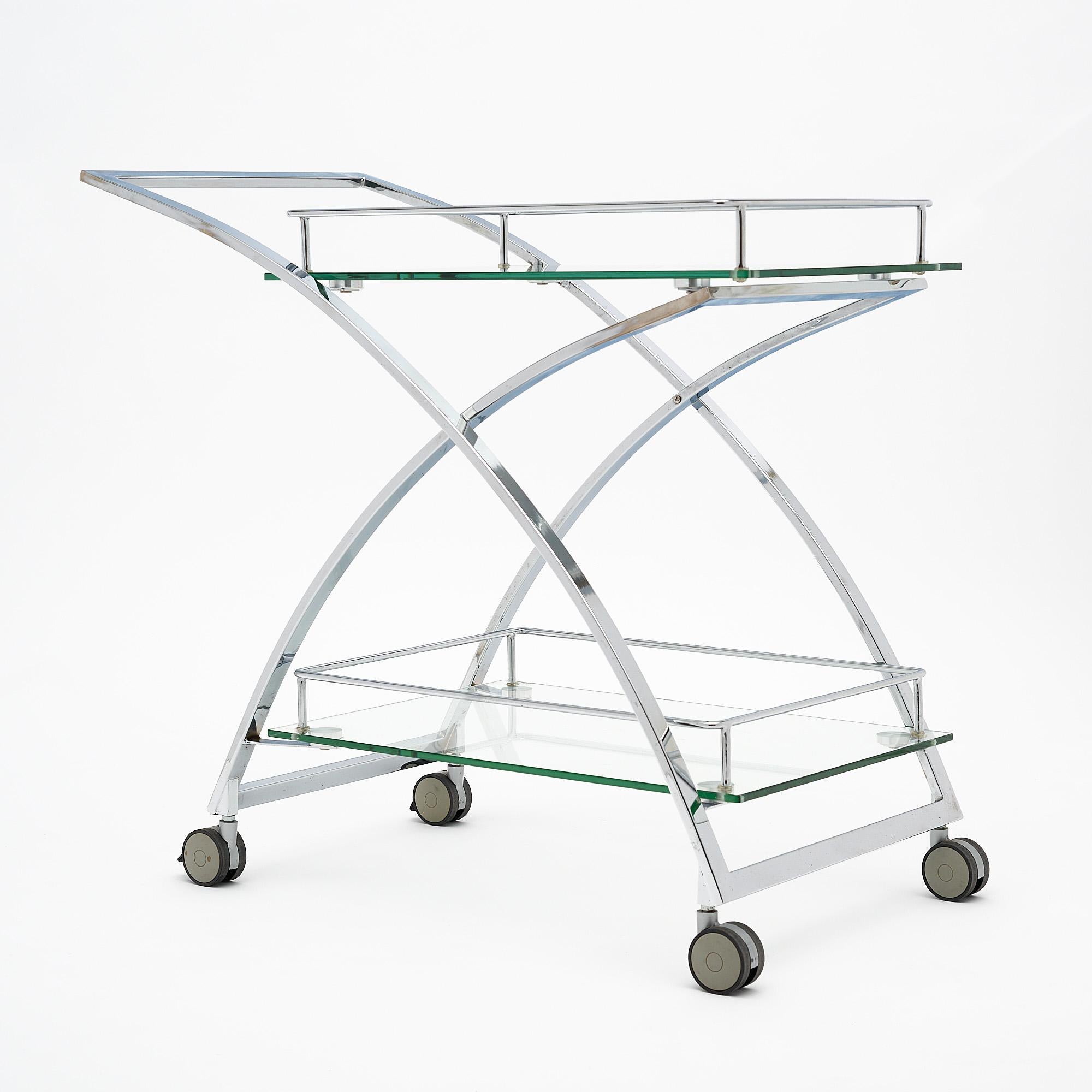 Bar cart, French, of chromed steel. The modernist bar cart features two thick glass shelves and is supported on casters.