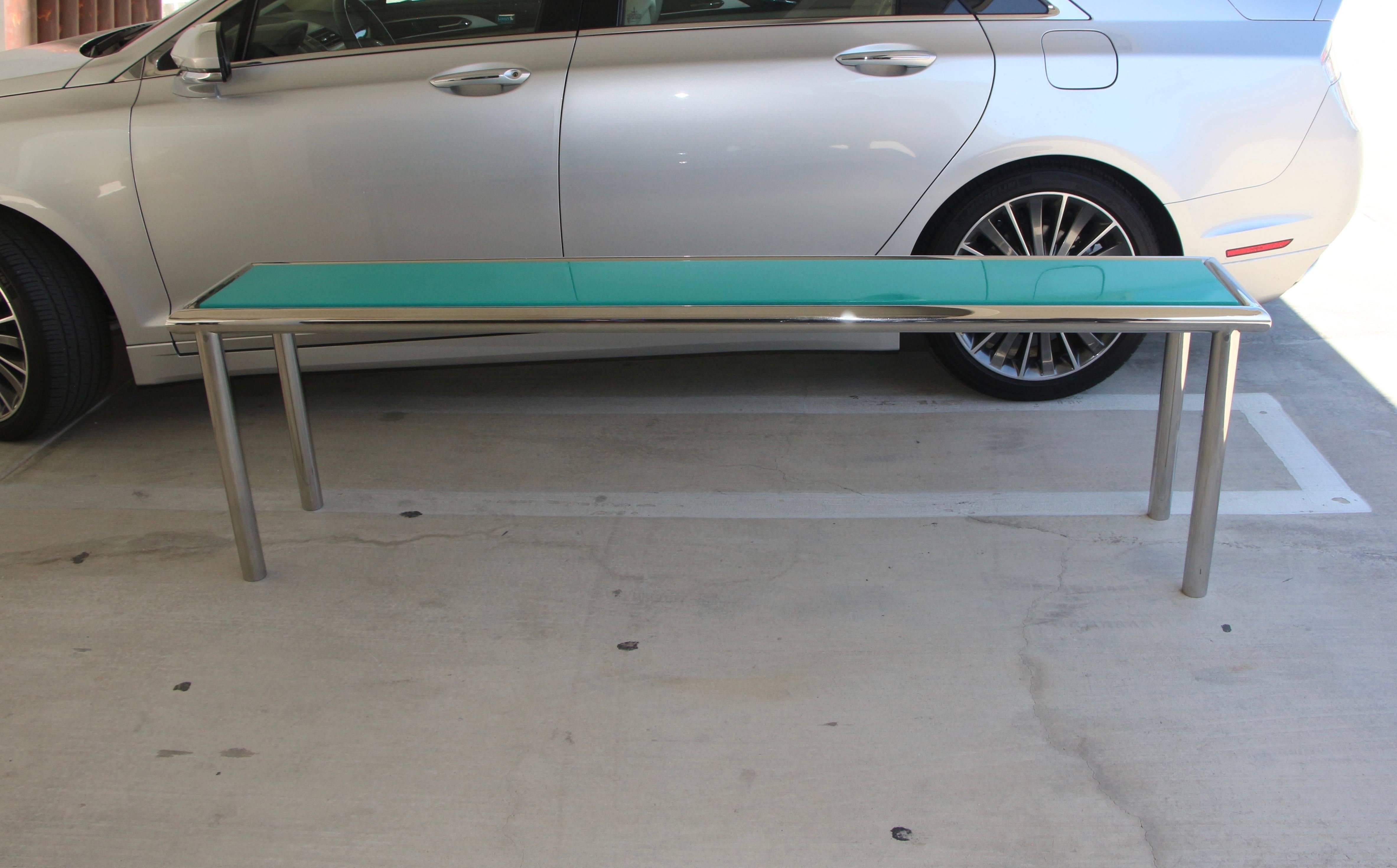 A nice interesting sofa table or console that is 7 feet long. It has a chrome tubular frame with a highly lacquered wood top in a shade of turquoise. It is quite sturdy as you can see from the support system in the picture taken from below. The