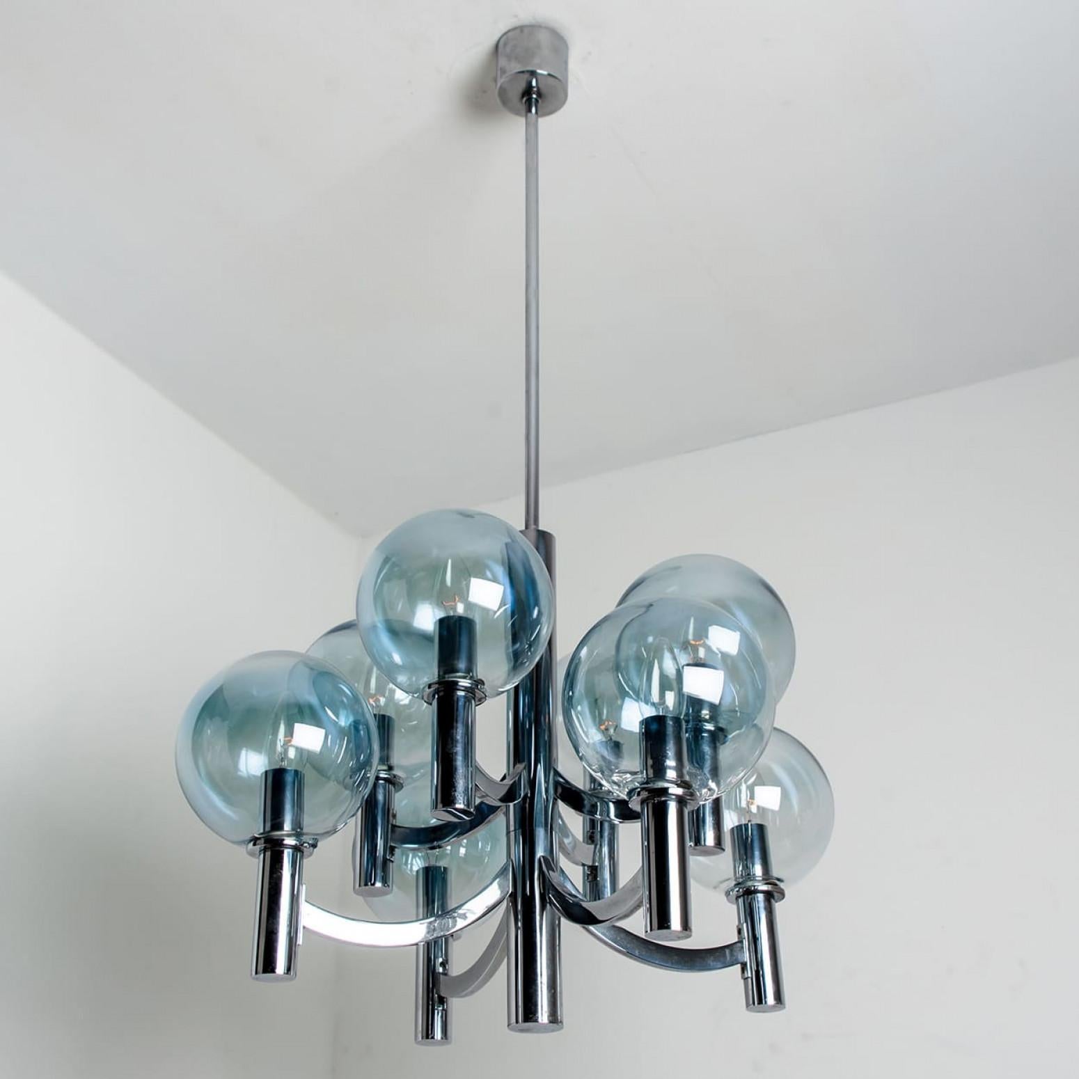 Maravillosa lámpara de araña con cuencos de cristal azul claro y base y accesorios cromados. Fabricado en la década de 1970 con el estilo Hans-Agne Jakobsson. Ilumina maravillosamente.
La araña tiene 8 bombillas de cristal en tonos azules fijadas en