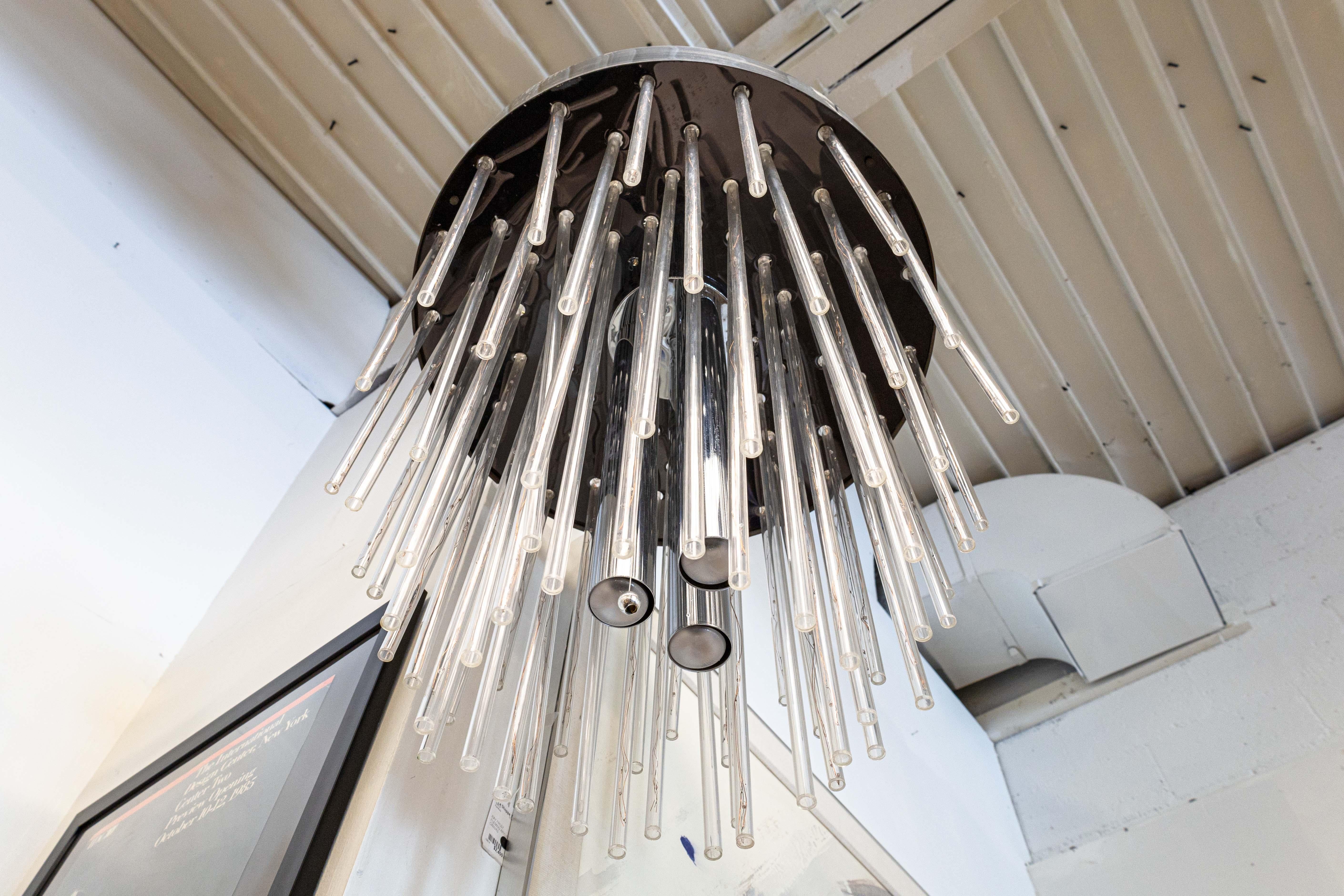 Un lampadario a cascata in cromo e lucite. Si tratta di una splendida lampada dallo stile e dai materiali contemporanei. Questo pezzo presenta una serie di aste in lucite acrilica di diverse dimensioni con LED che rivestono l'interno. Al centro del