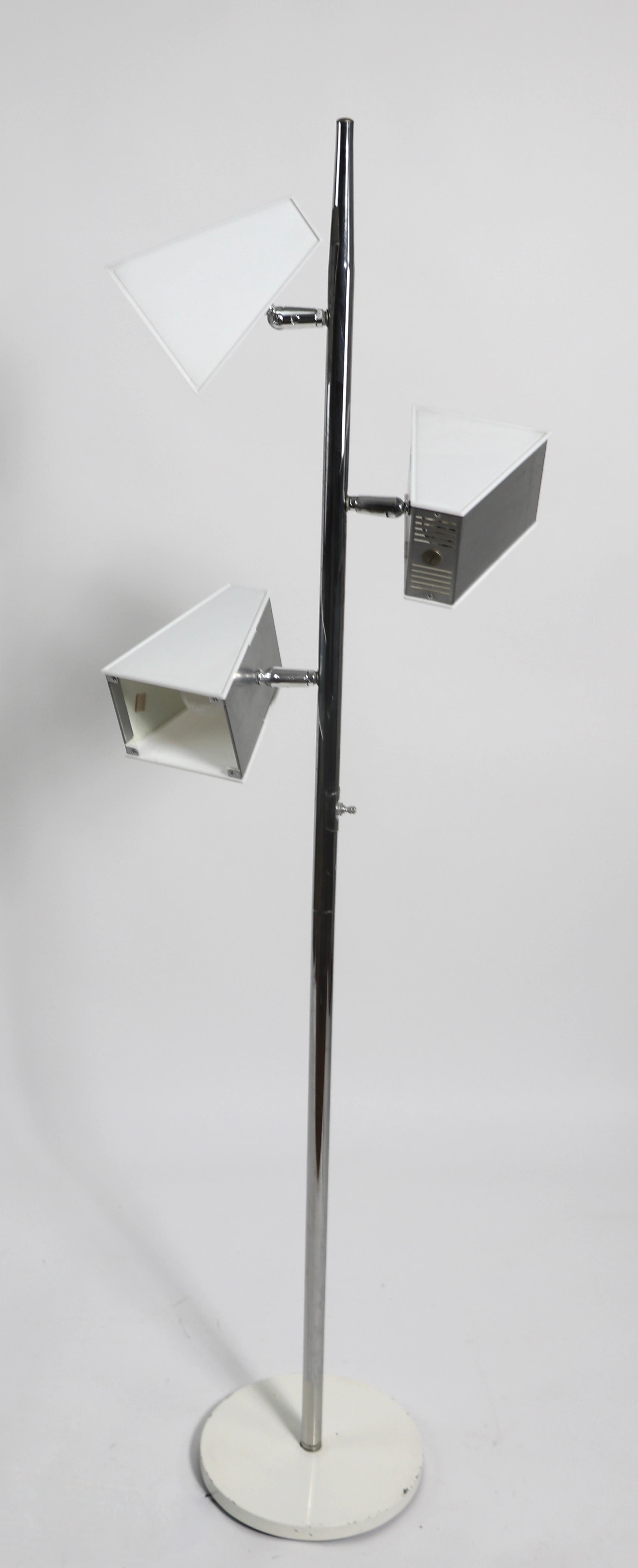 Three light pole lamp having triangular shades, of translucent white lucite and brushed steel mounted on a bright chrome pole. Each shade measures 7 D x 5.5 W x 4.25 H inches - and is adjustable in position to direct the light. The lamp features a