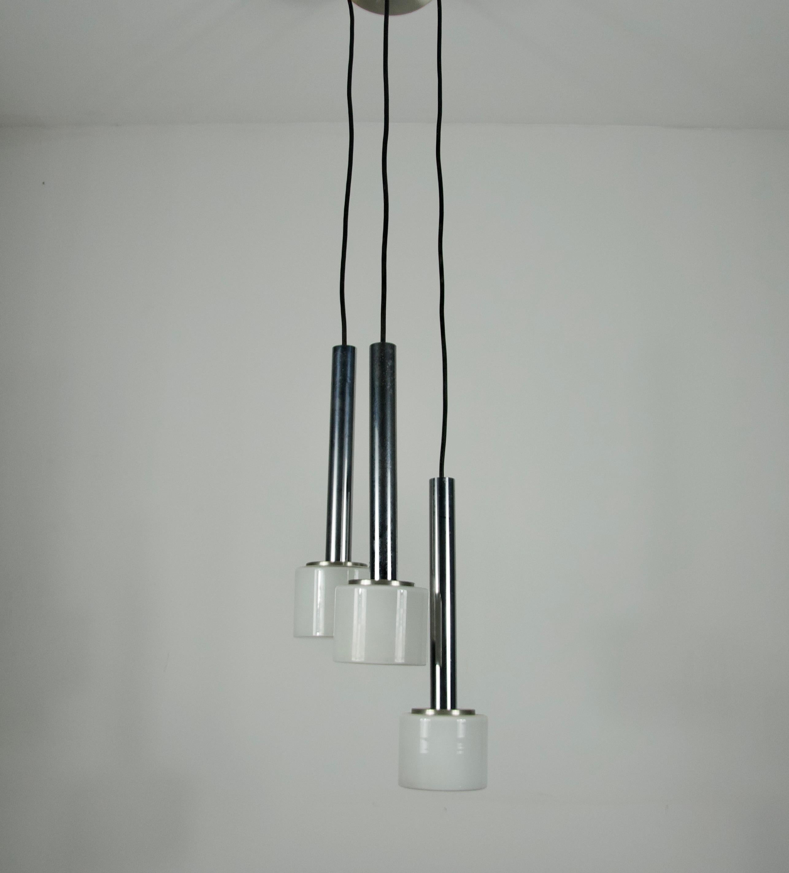 Questa straordinaria lampada a sospensione a cascata degli anni '70 incarna le linee pulite e la raffinata eleganza del design tedesco moderno della metà del secolo. Caratterizzata da tre steli cilindrici cromati, ciascuno dei quali termina con un