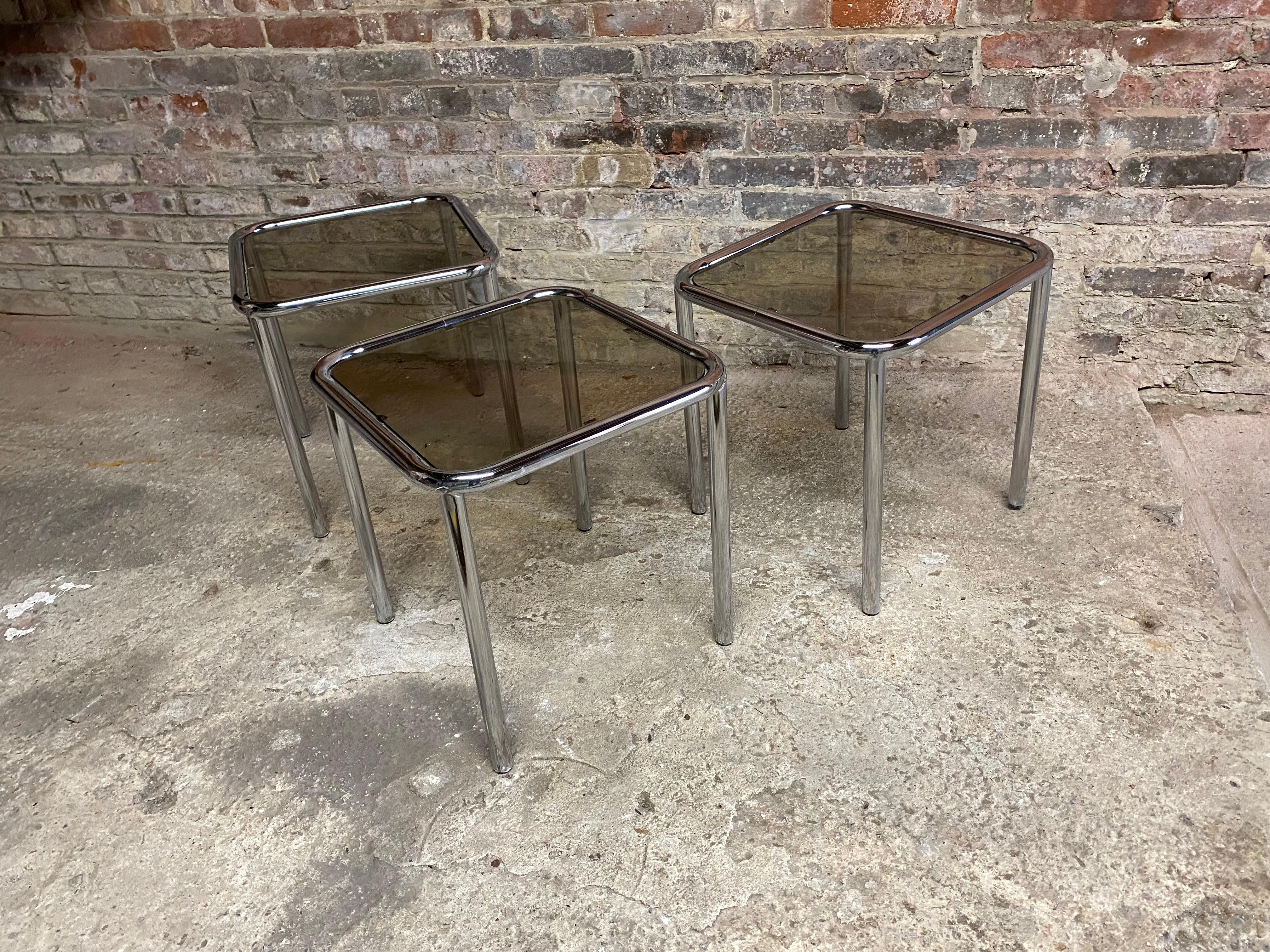 Circa 1970 tubular chromed steel and smoked glass nesting tables by Arthur Umanoff for The Ansley Collection. J818/Nest. They can be safely stacked to free up space. Glass and chrome are in good overall condition. Structurally sound and sturdy.