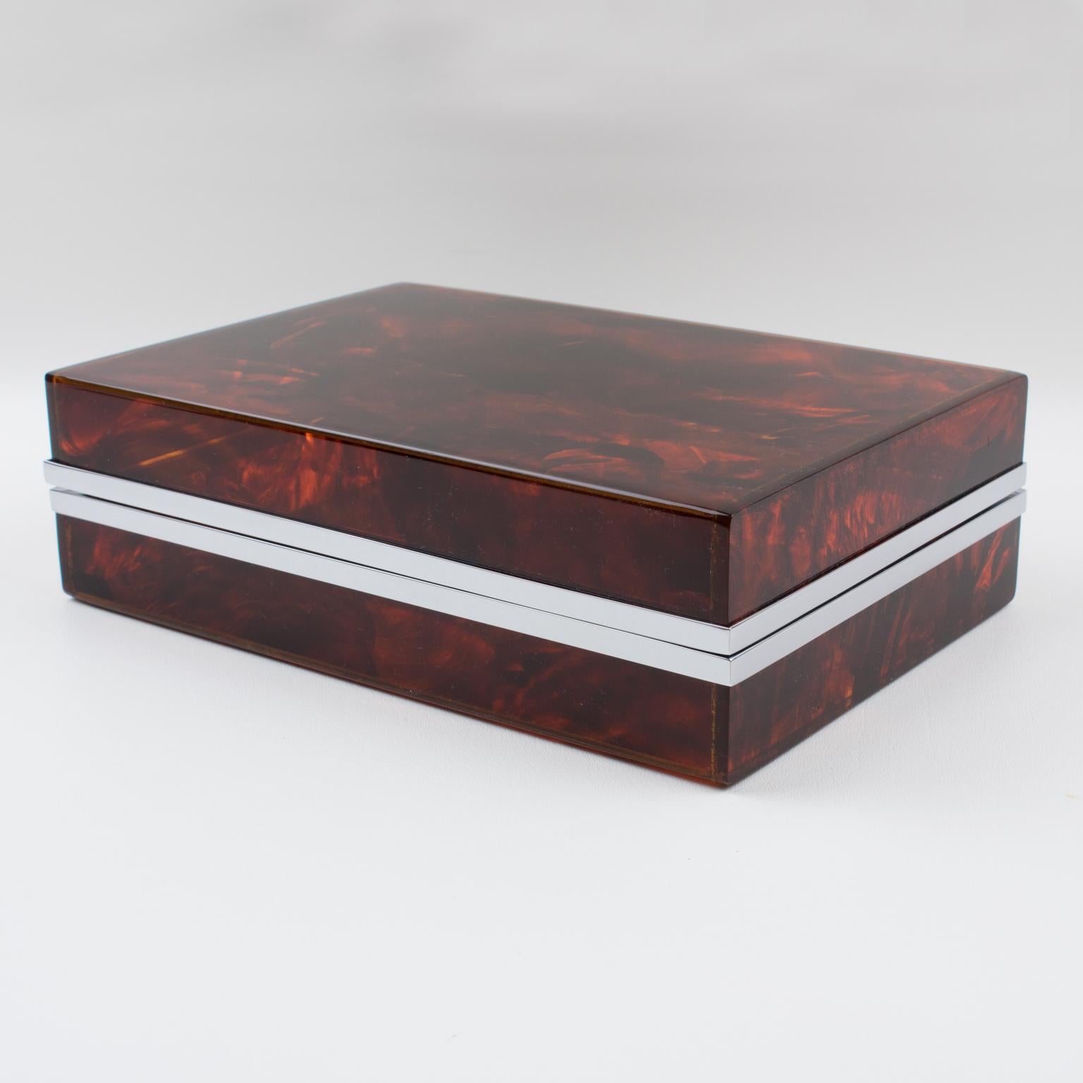 This decorative lidded box, crafted circa 1970, is perfect for a living space or vanity. The piece boasts a chrome-plated framing with Lucite in a tortoiseshell (tortoise) textured pattern. With impressive quality and a lovely translucent changing