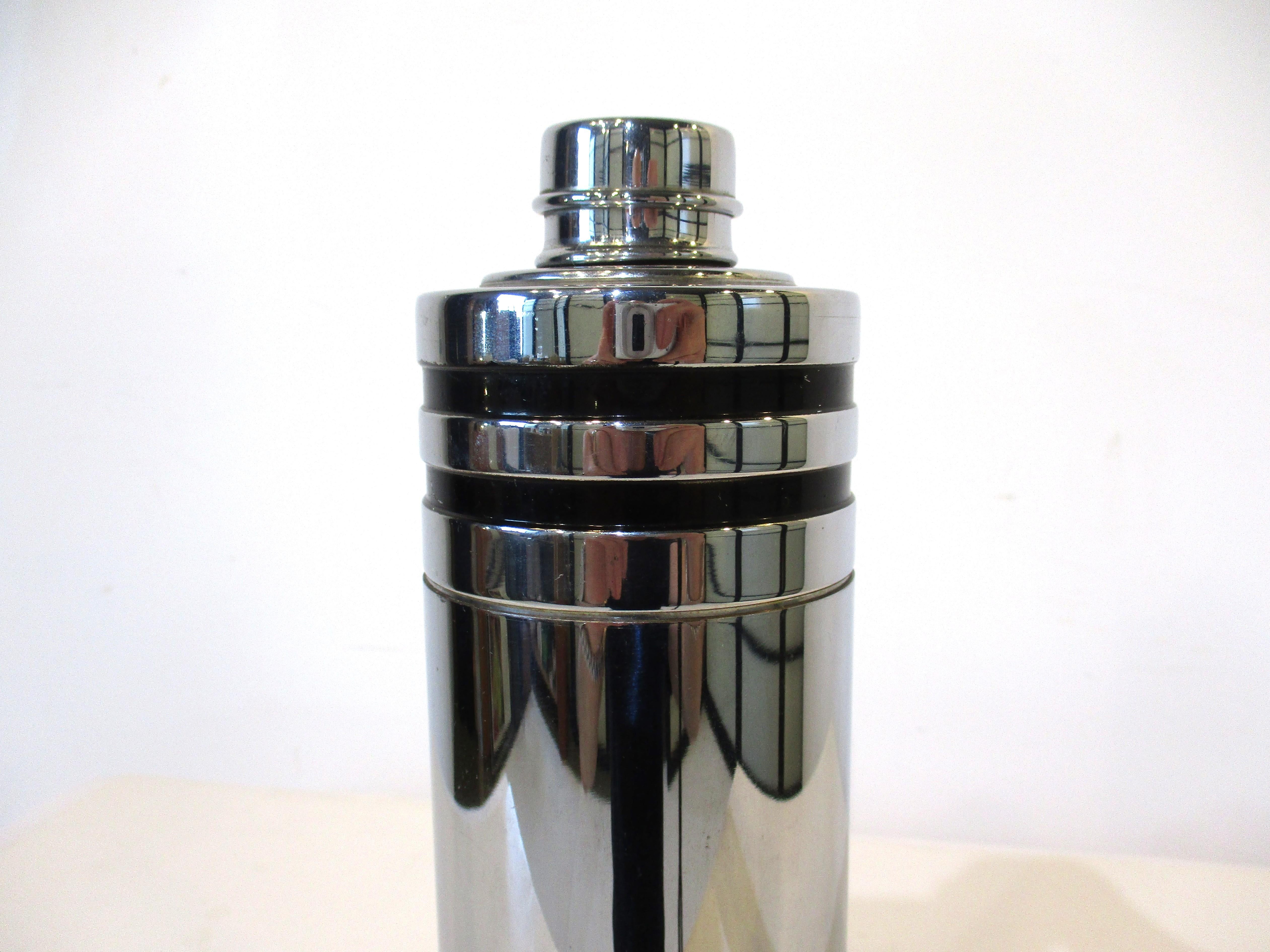 A very nice chrome cocktail shaker with black ring details to the body, small removable cap to the lid with built in strainer. This Art Deco piece was manufactured by the Everlast company.