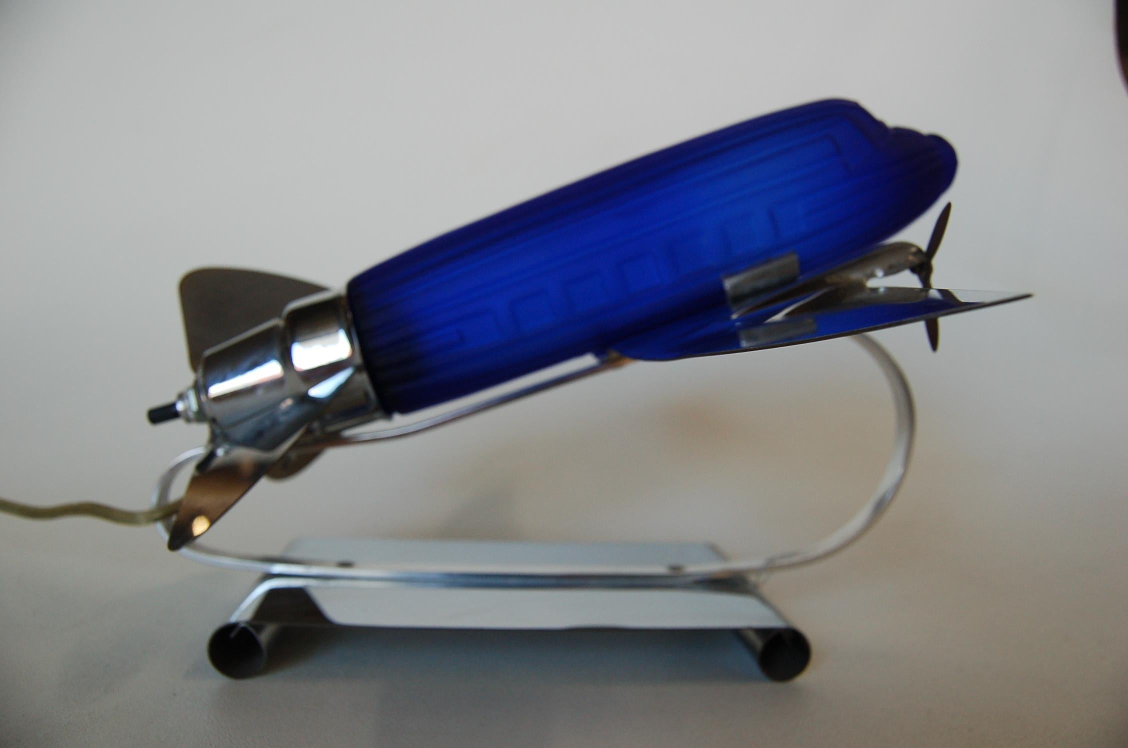 Art Deco style airplane table lamp in blue glass and chrome. This rare highly collectible accent lamp by NY company Sarsaparilla was made in the 1970s modeled after Dakota DC-3. 

The shiny chrome propellers spin. 8