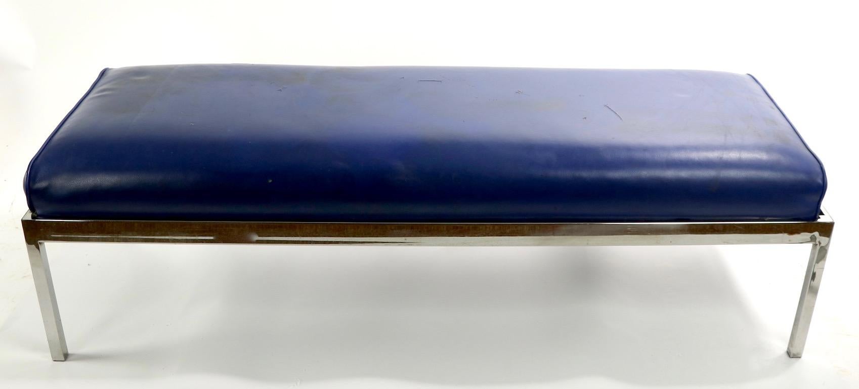 Rectangular chrome base bench with blue vinyl upholstered seat. The bench has a squared chrome base and thick 
( 4 inch ) upholstered pad top. This example shows some cosmetic wear, the top pad has various rips etc, and chrome finish shows minor