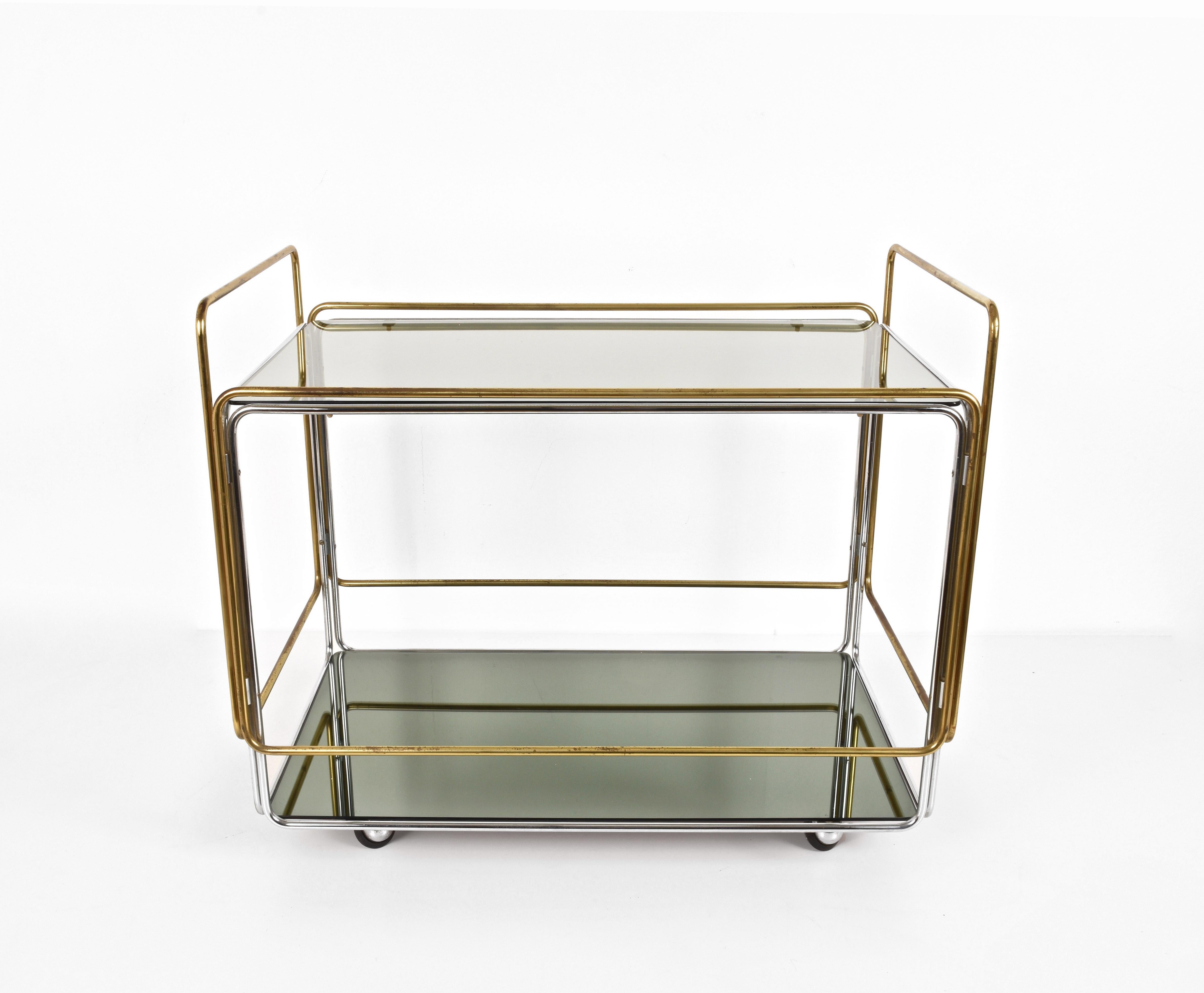 Attributable to Fontana Arte
Superb linear service trolley. On two levels. One in smoked glass, the other is a smoked mirror.
The frame is tubular in brass and chrome, rectangular in shape.