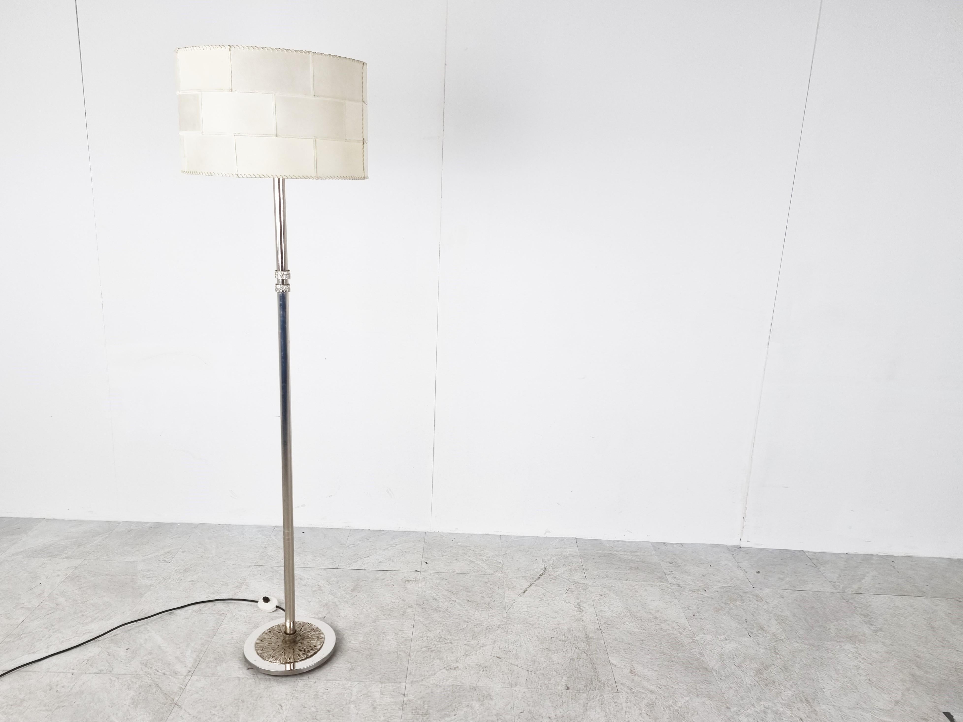 Unique chromed metal floor lamp.

It has a nice sculpted brutalist style base and also features two brutalist design details in the middle of the chromed rod.

The lamp has an original seventies patchwork parchment lamp shade which emits a dim