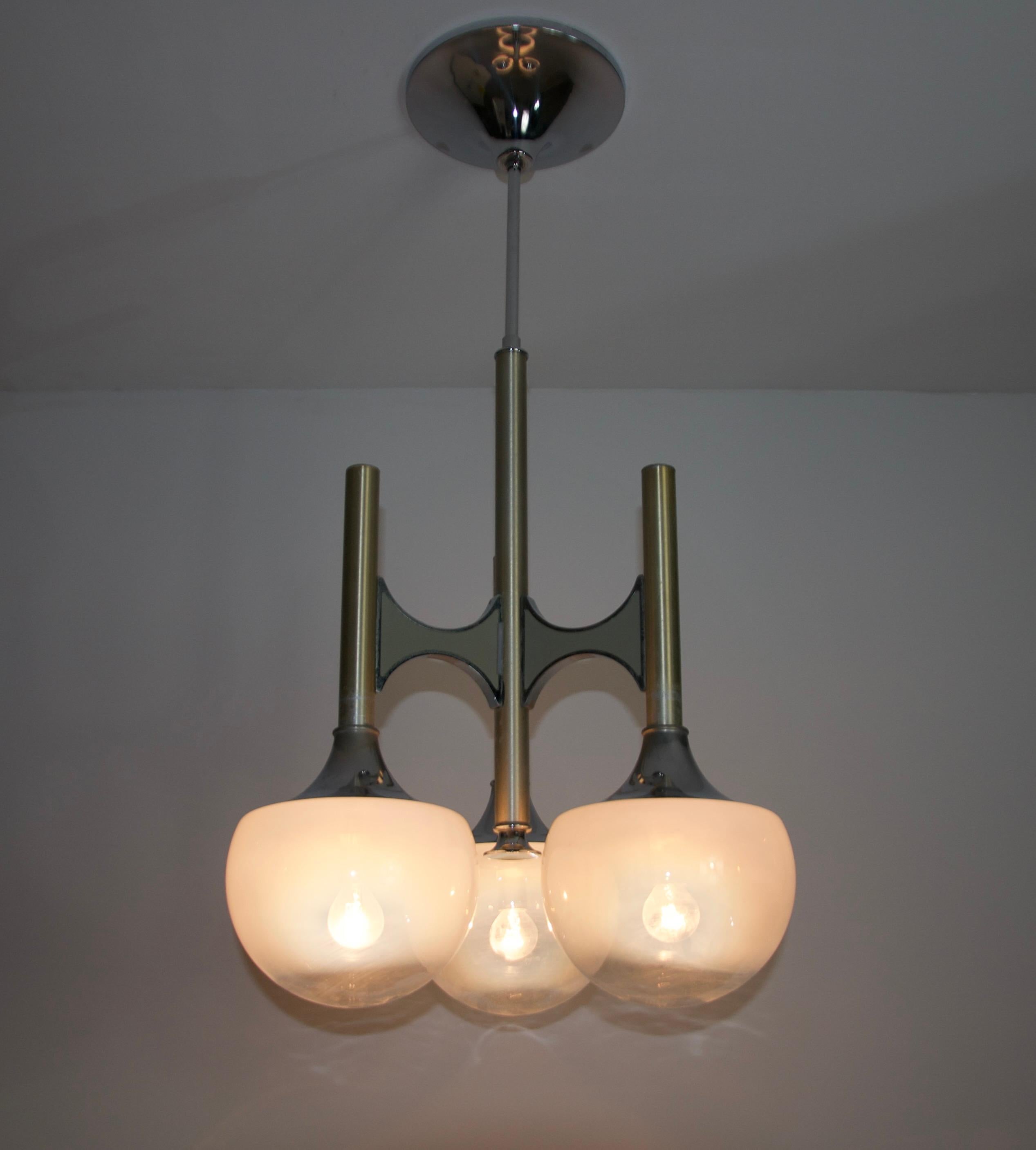 This exquisite chandelier, designed by renowned Italian lighting designer Gaetano Sciolari in the 1960s, is a stunning example of mid-century modern elegance. Featuring a sophisticated combination of brass and chrome elements, the fixture boasts a