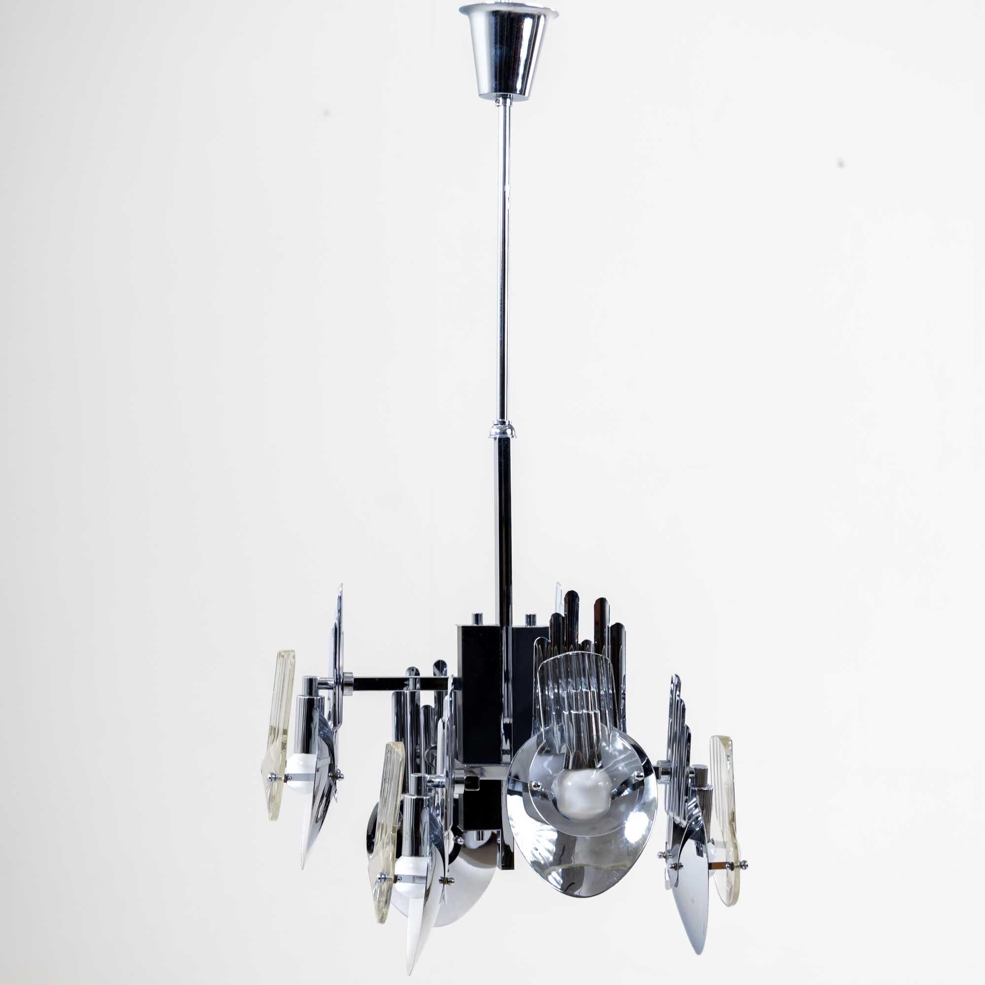 Six-armed chandelier made of chrome-plated metal by Oscar Torlasco. The light bulbs are mounted between thick glass panes and concave metal discs. The reflected light creates interesting effects.