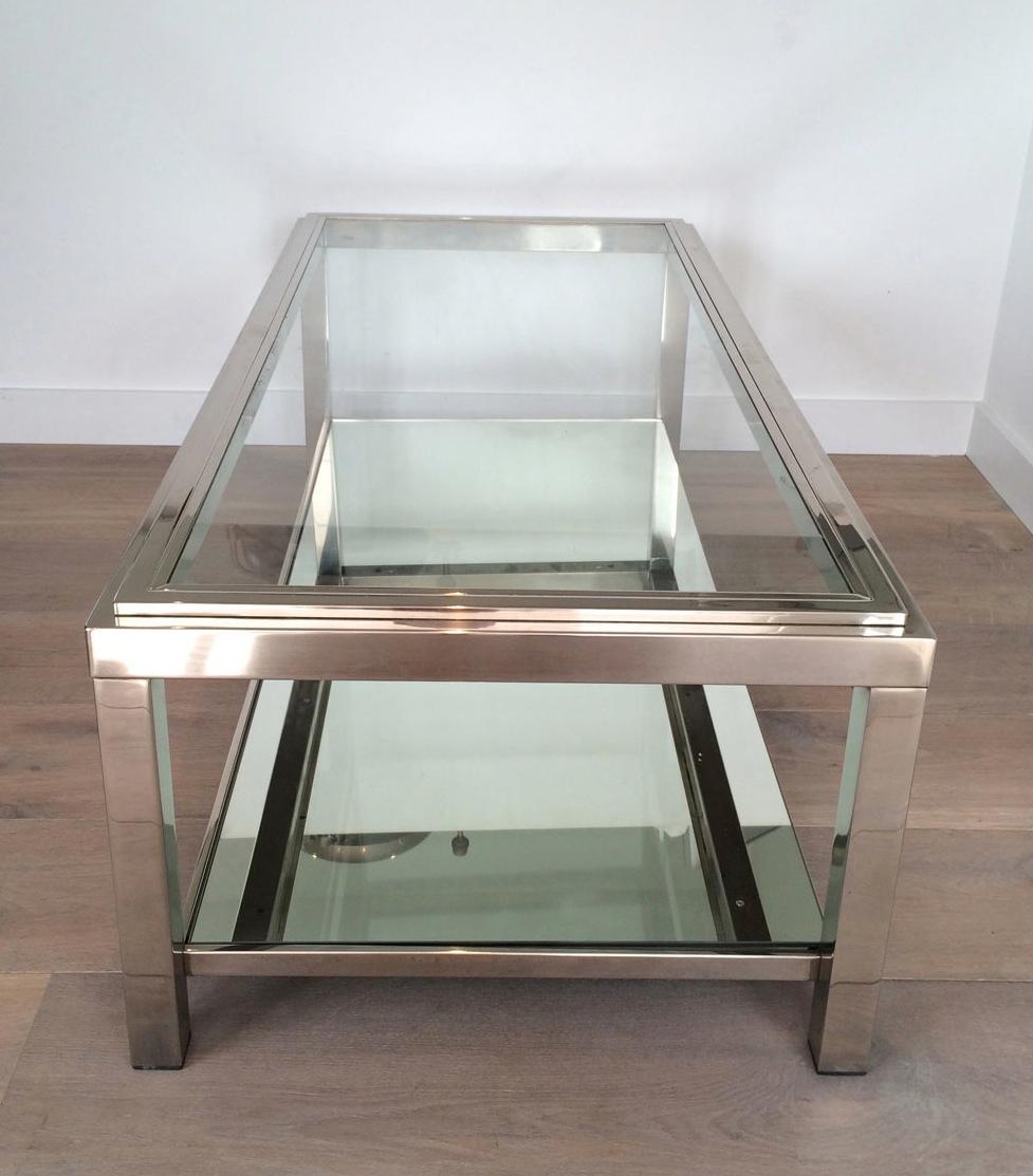 This coffee table is made of chrome with a clear glass shelf on top and a mirror on the bottom part. This is a French work. Circa 1970.