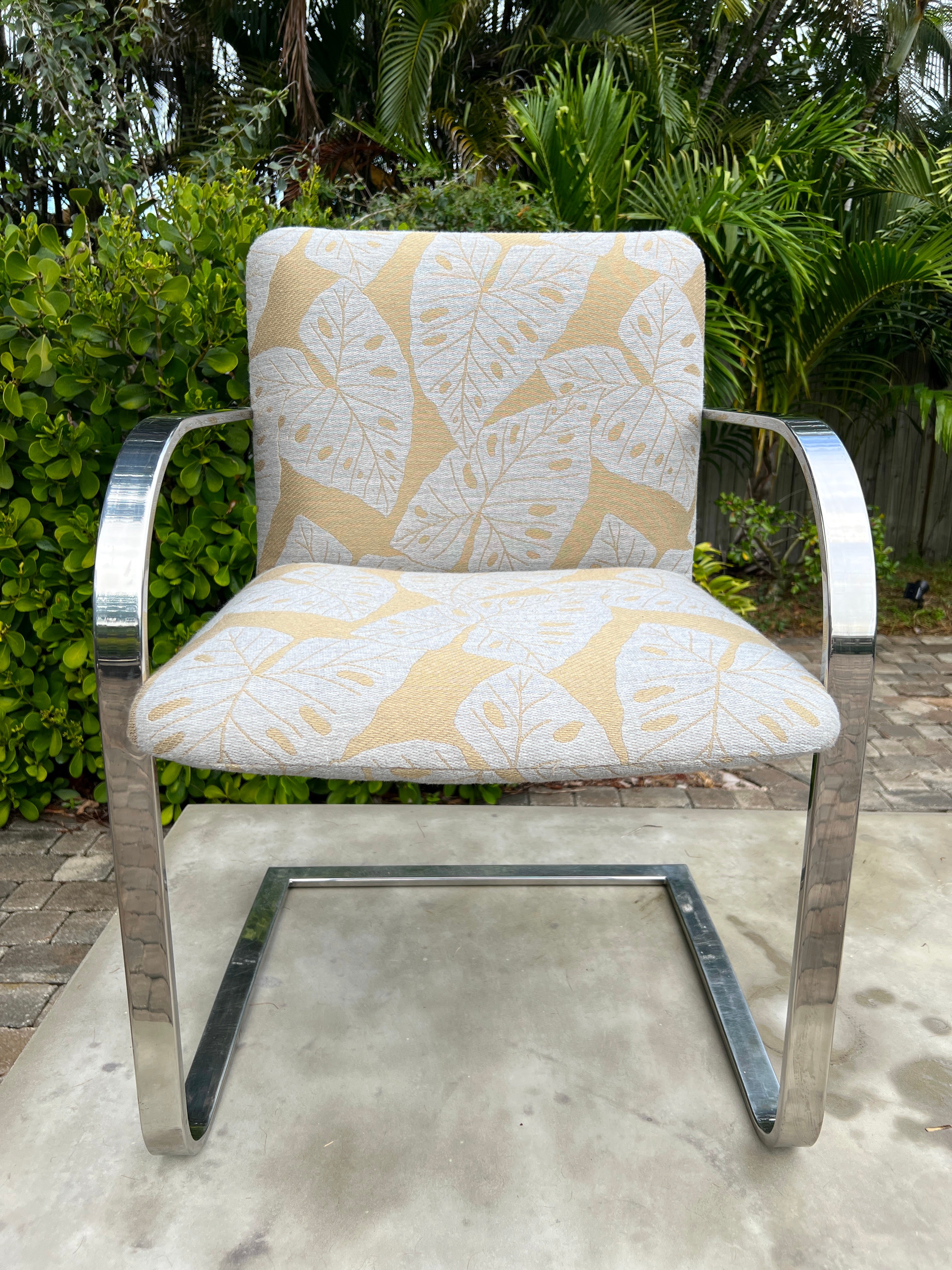 Mid-Century Modern desk chair or side chair with cantilevered steel frame in chrome. Chair has streamlined profile with curved armrests and floating seat design. Newly upholstered in handwoven fabric with bold coastal or tropical leaf print in hues