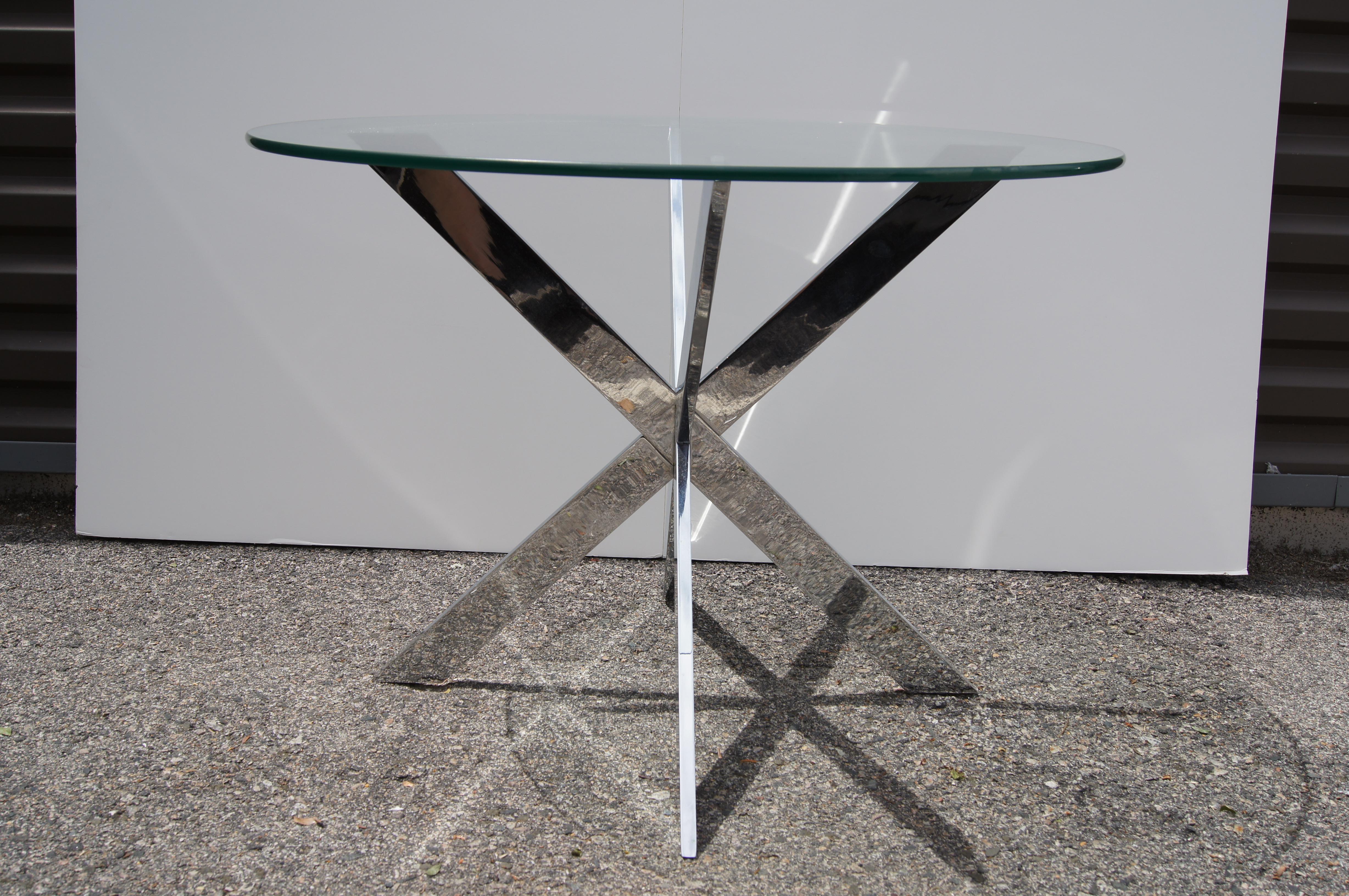 Leon Rosen designed this sleek and polished side table for Pace Collection. Intersecting Xs of chrome-plated steel form a starburst base on which floats a round glass top.