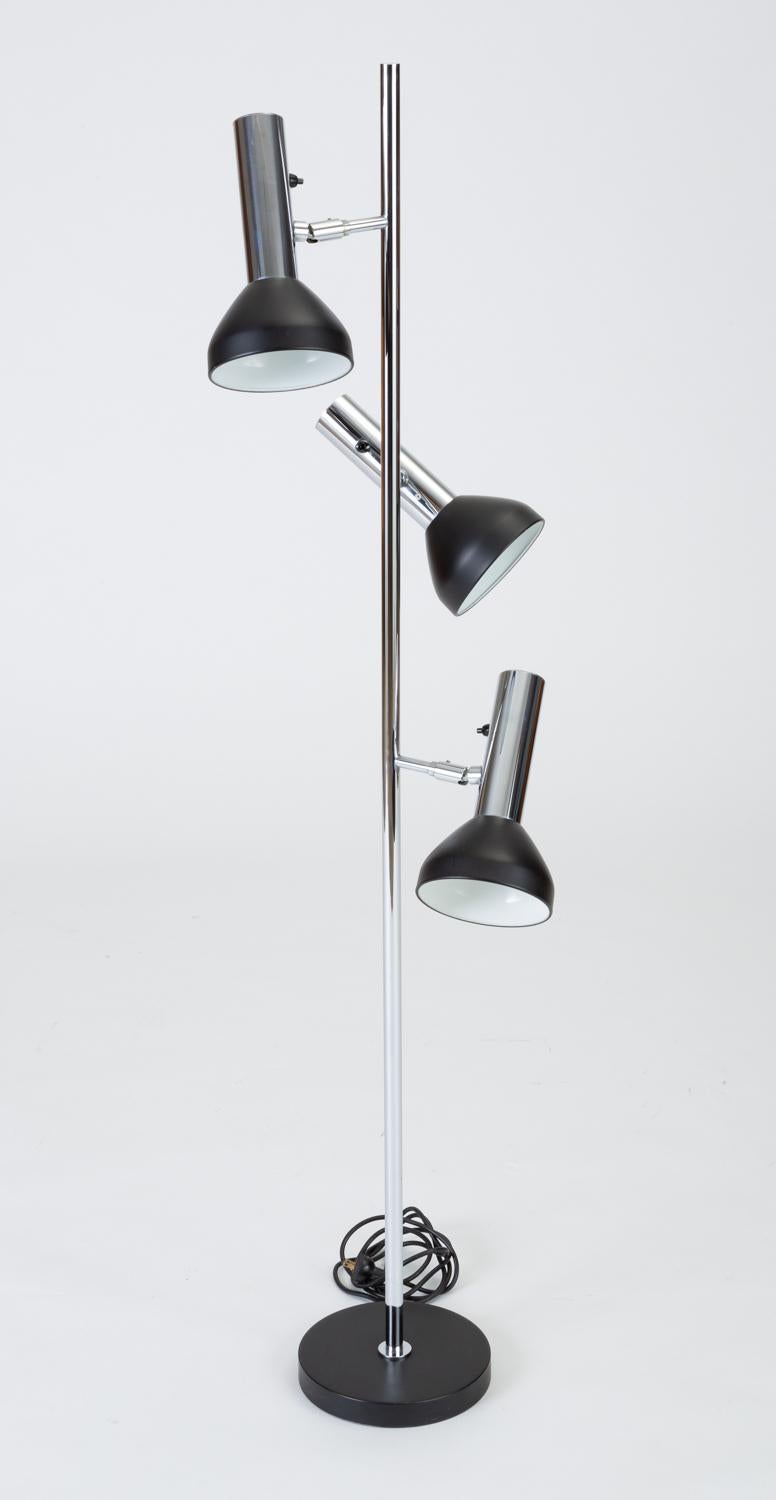 A sharply minimal floor lamp by German company Gebrüder Cosack. Manufactured in the early 1960s, the lamp has three spotlight shades extending from a central chrome pole. Each light operates on its own individual push-switch for maximum control over