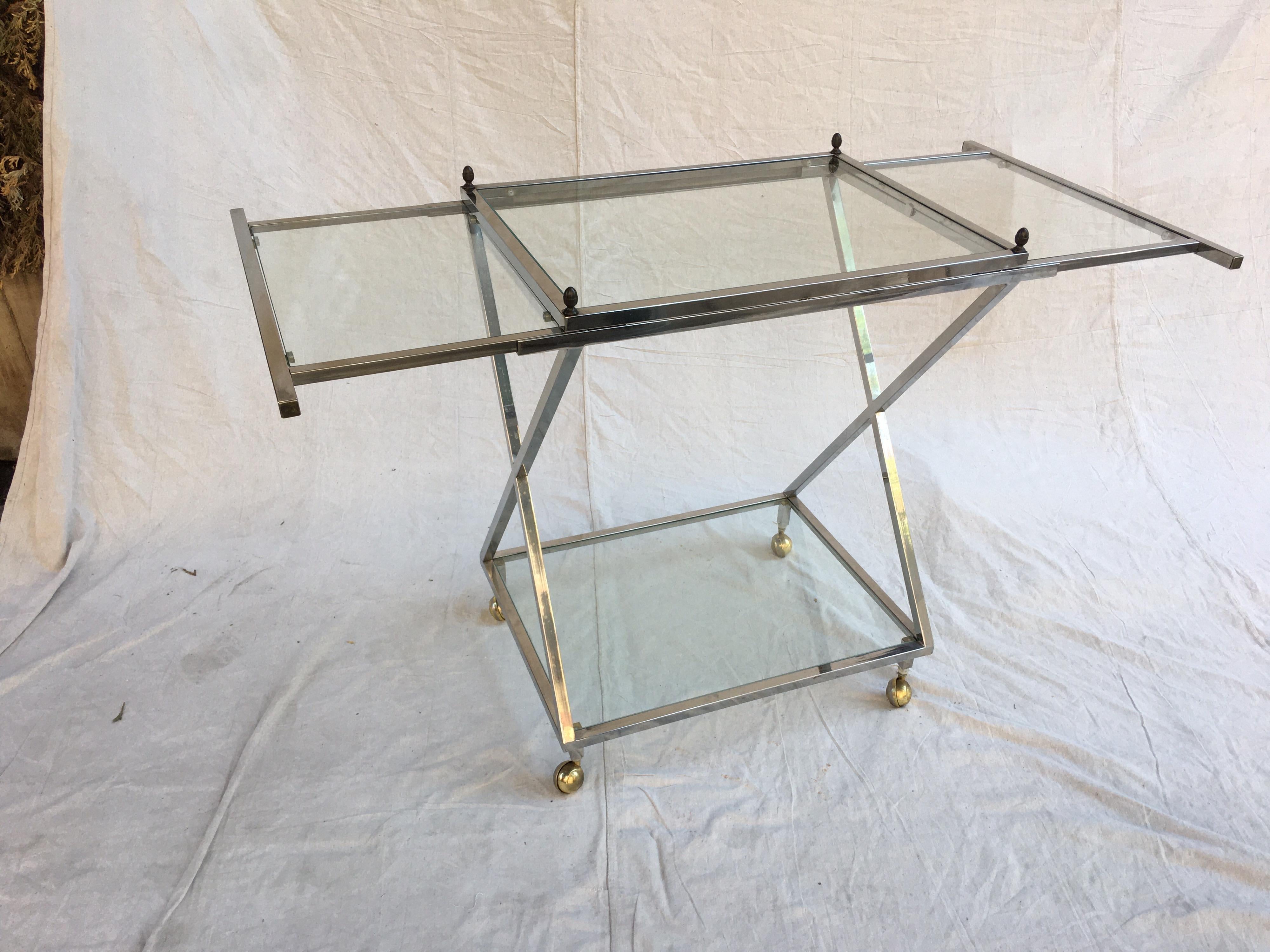 1970s chrome and glass bar cart with brass finales at each corner. Glass leafs pull out from each end to allow for ample work space. Each leaf is a little over 12