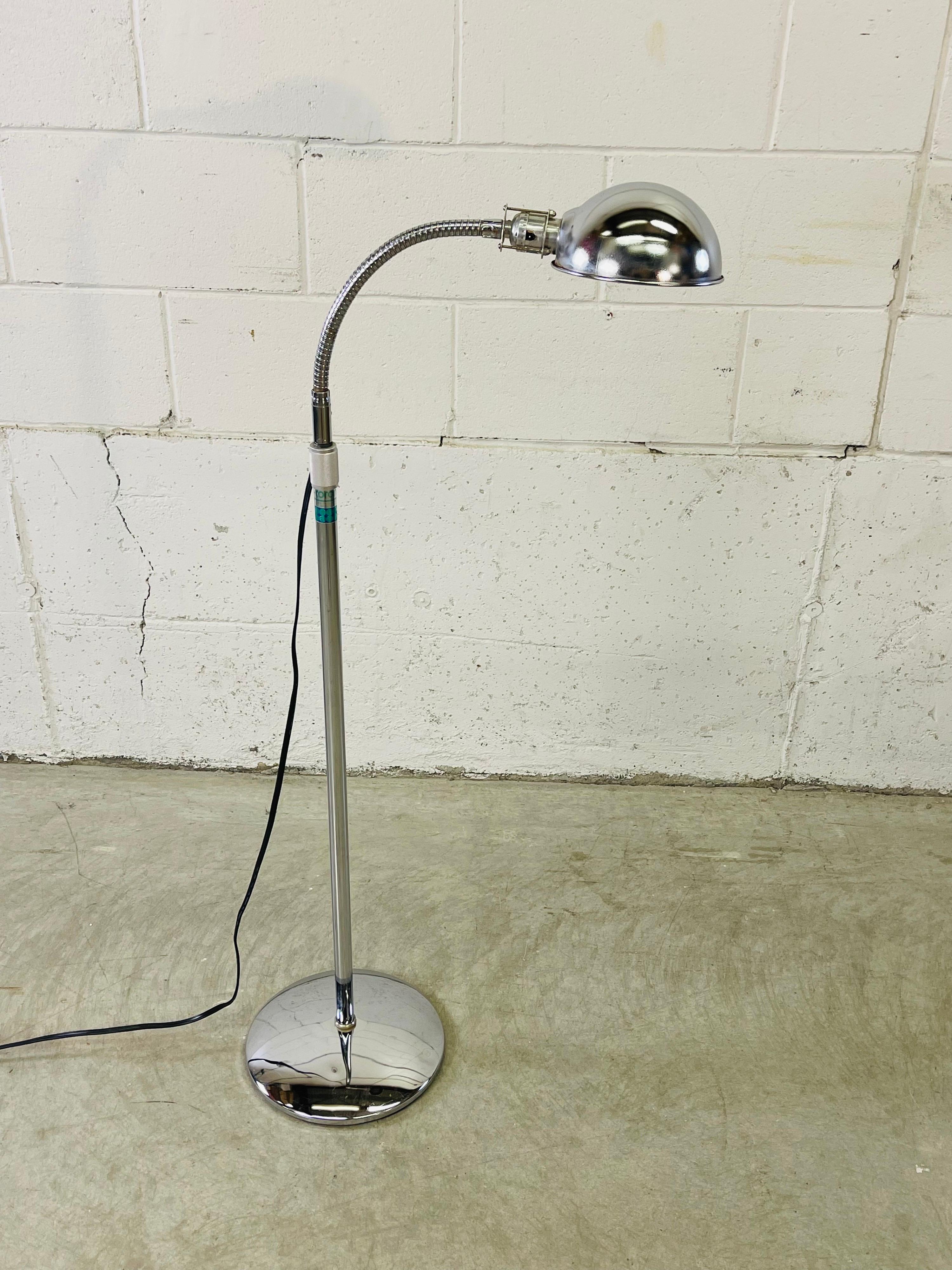 Verchromte Schwanenhals-Stehlampe mit rundem Sockel. Die Lampe lässt sich auf eine maximale Höhe von 66