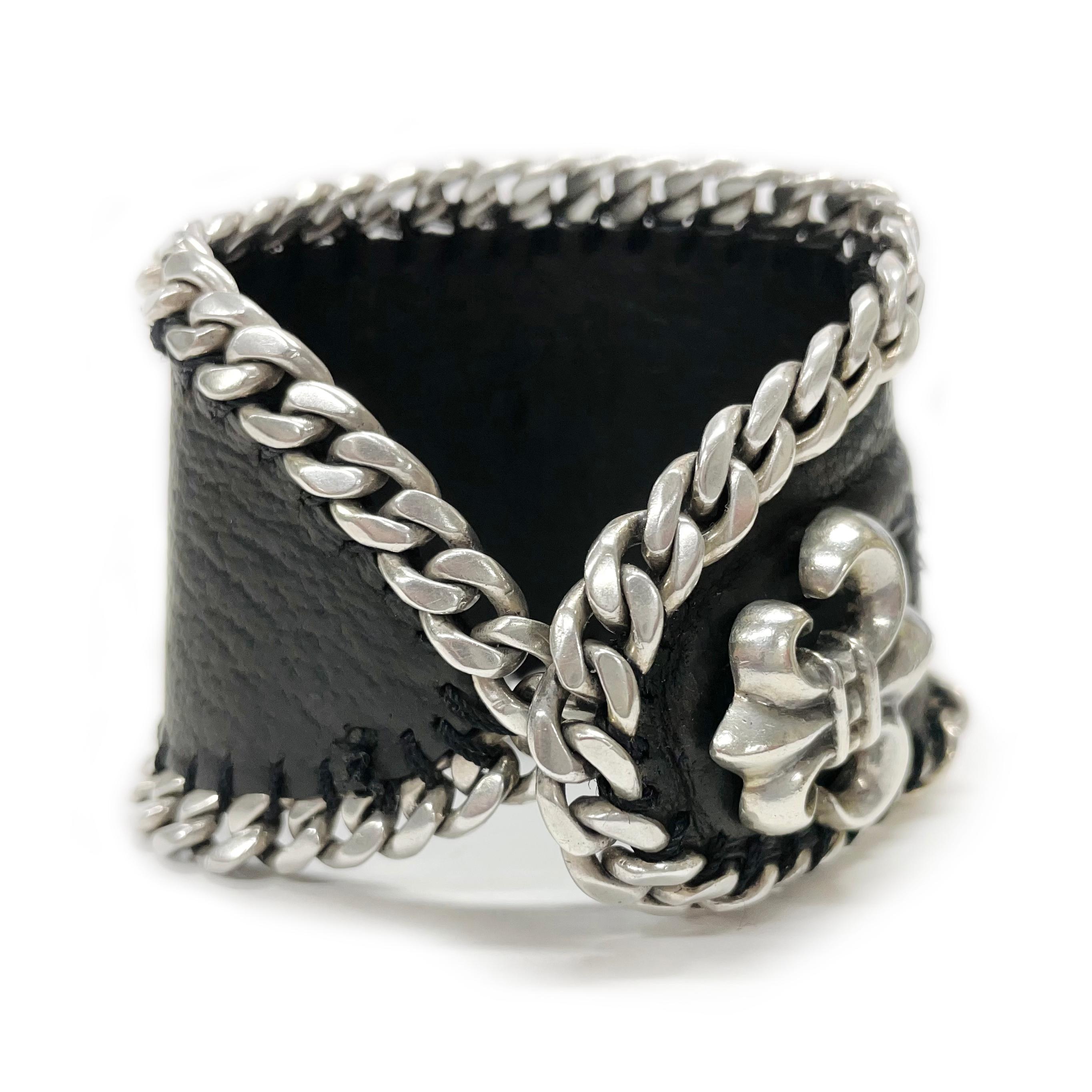 Chrome Hearts Silver Fleur de Lis Leather Bracelet. This unique bracelet features 925 silver curbed chain sewn into the edge of the black leather with a Silver Fleur de Lis charm serving as the toggle for the closure. Stamped on the charm/toggle is