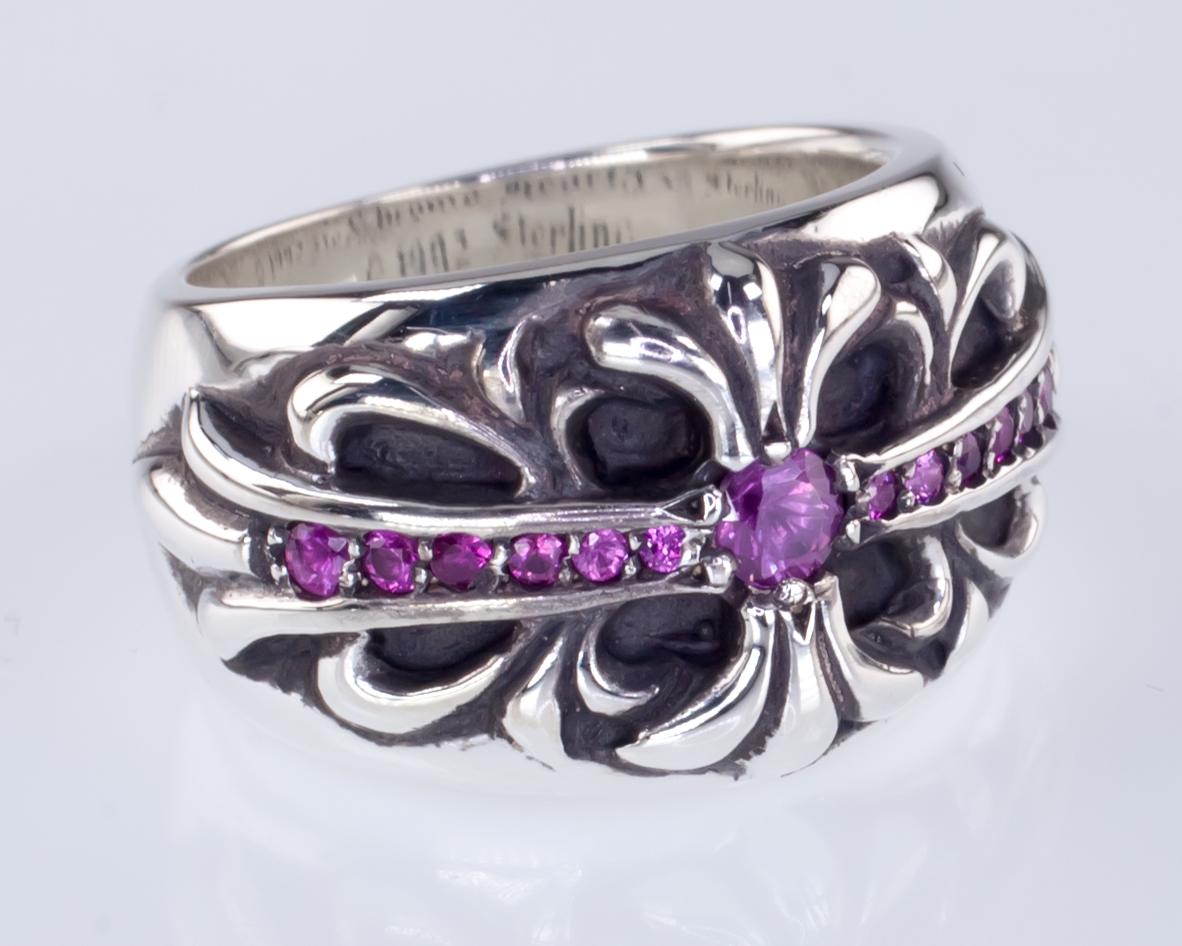 Gorgeous Chrome Hearts Ring
Features Maltese Cross Design and Pink Sapphire Accents
Created in 1992
Size 6
Front is 13 mm Wide
Band at Back is 7 mm Wide
Total Mass = 15.0 grams