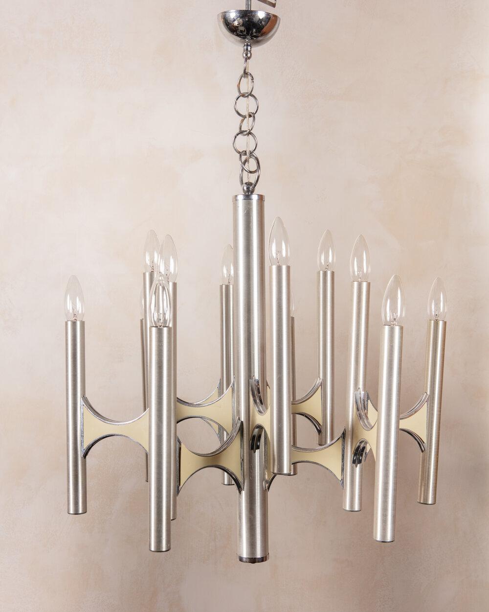 A sculptural 12 light chandelier attributed to prolific Italian lighting designer Gaetano Sciolari (1927-1994). This fixture features a brushed chrome metal frame with ivory enameled resin inserts. The ivory contrasts beautifully against the silver